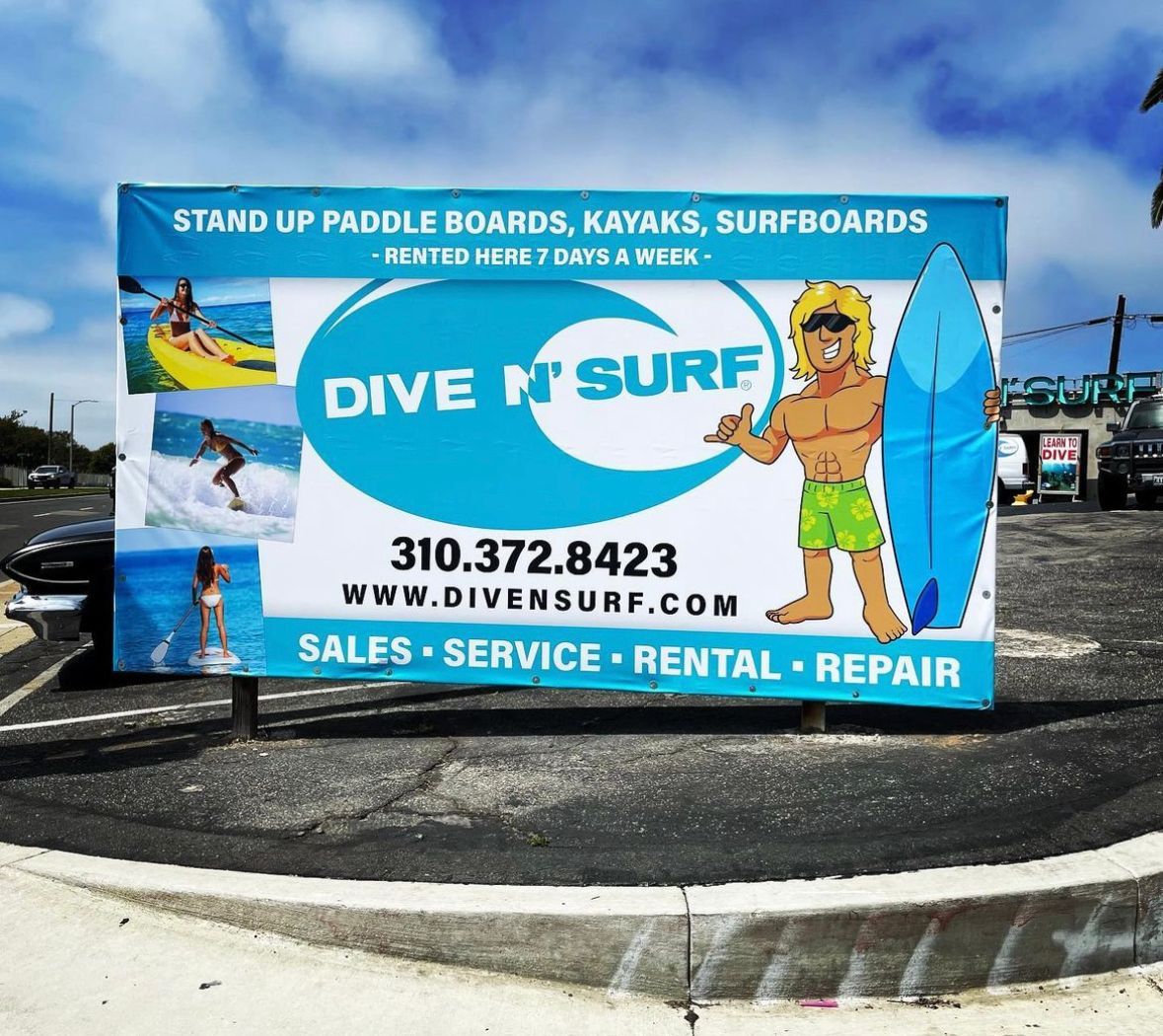 A billboard for dive n surf shows a man holding a surfboard