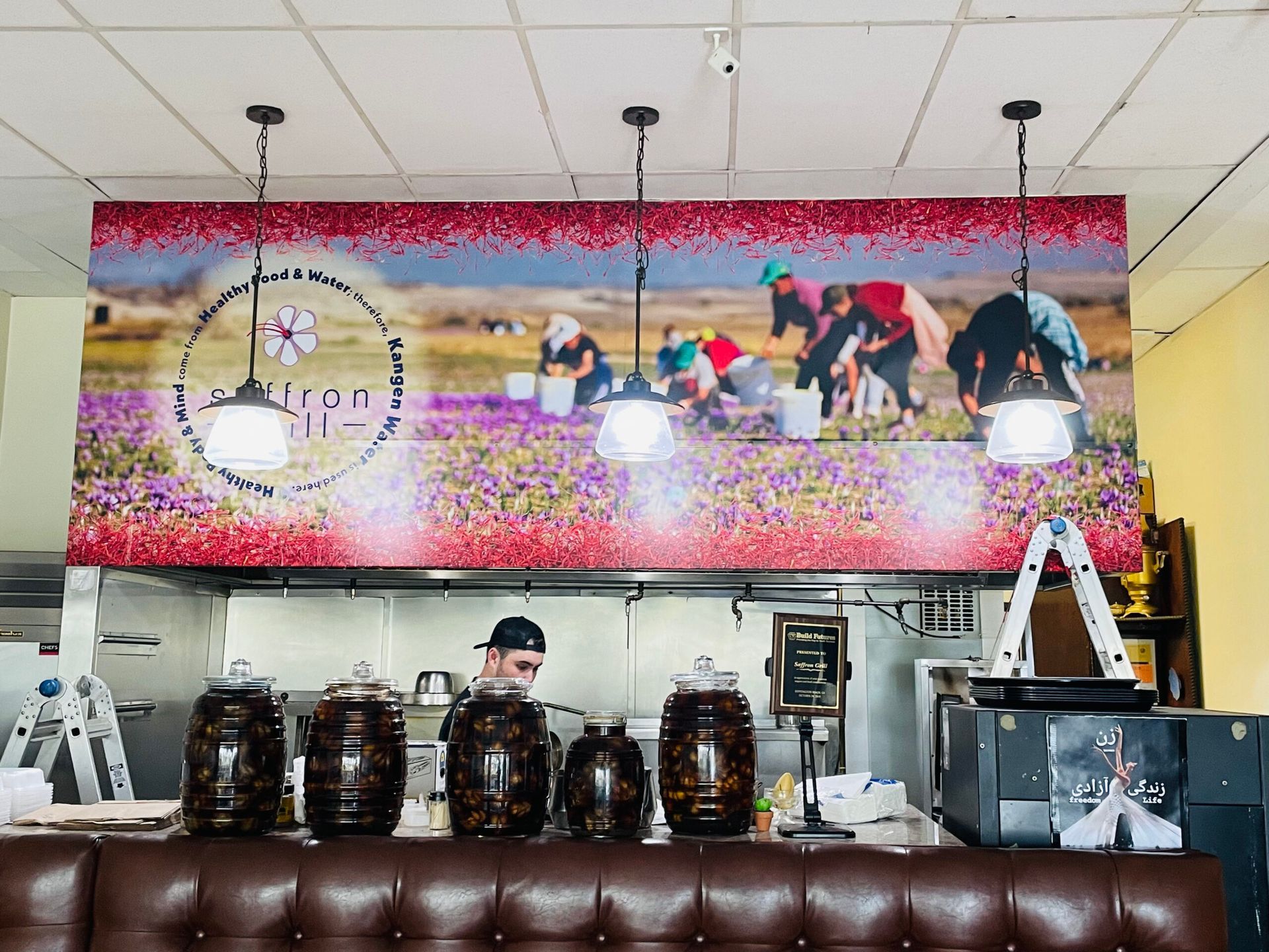 A man is standing in a kitchen with a large mural on the wall.