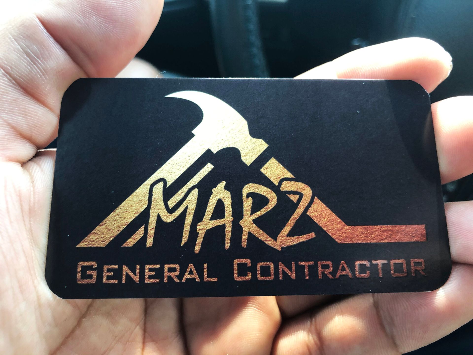 A person is holding a business card for marz general contractor
