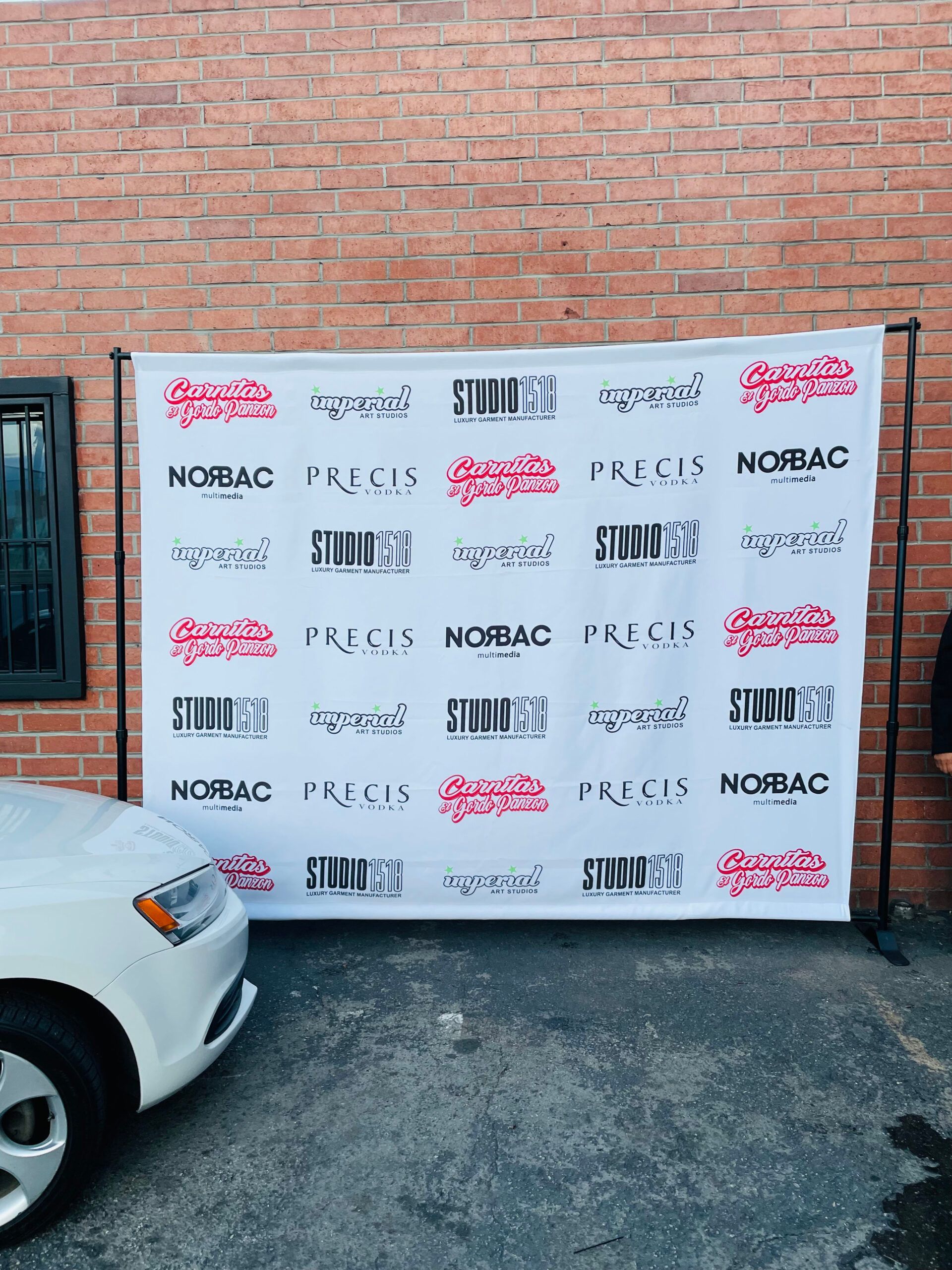 A white car is parked in front of a sign that says nobac