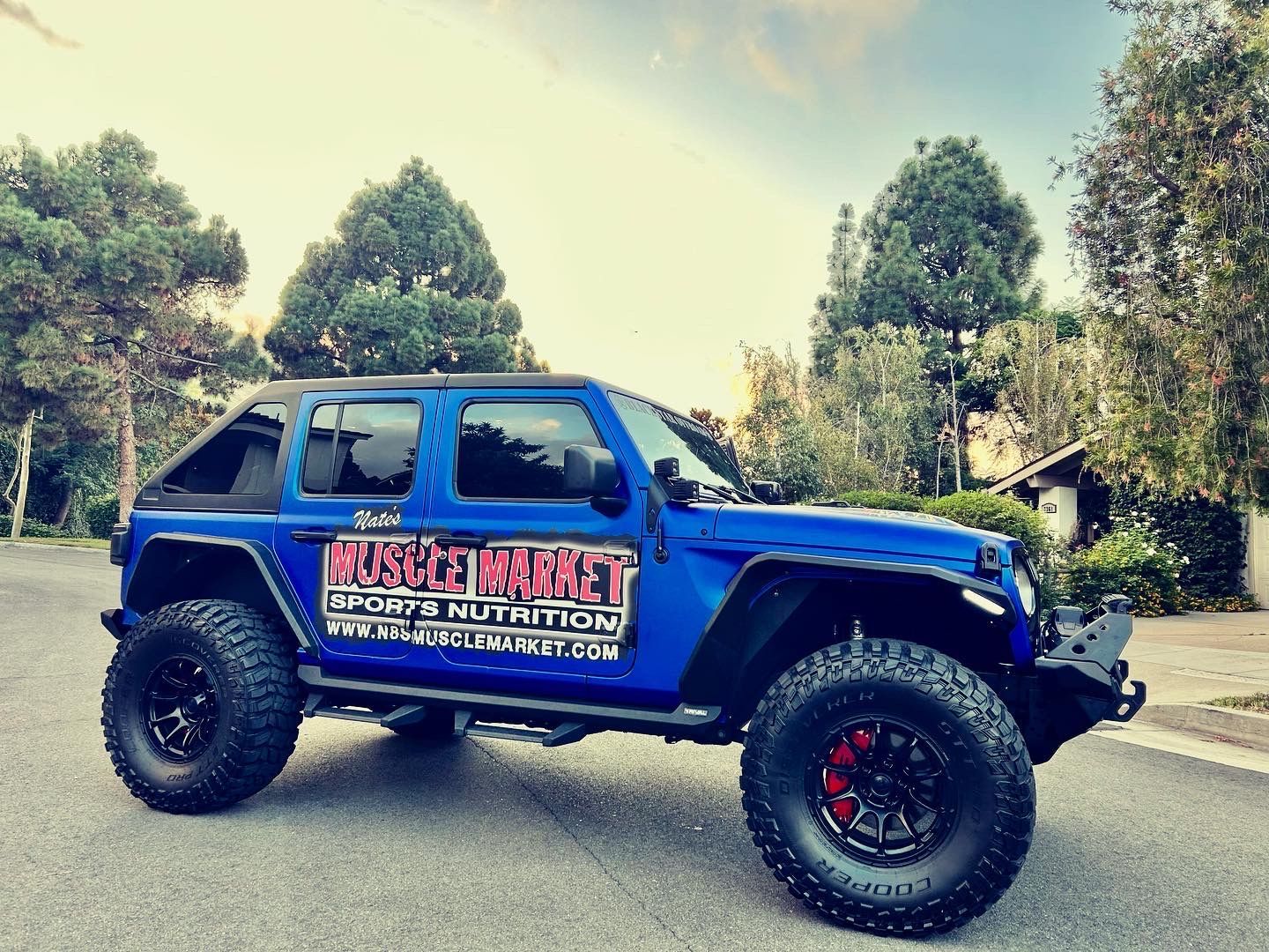 A blue jeep with muscle market written on the side