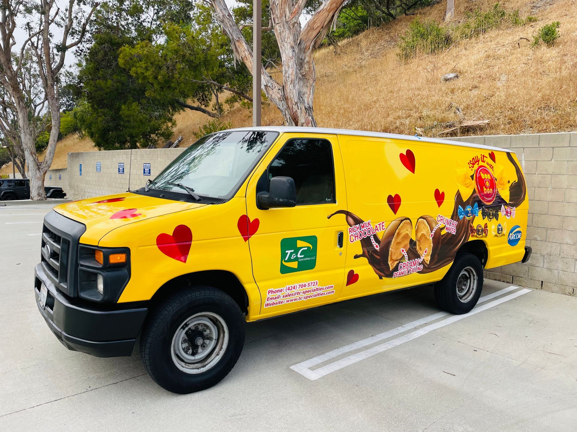 A yellow van with hearts on the side is parked in a parking lot.