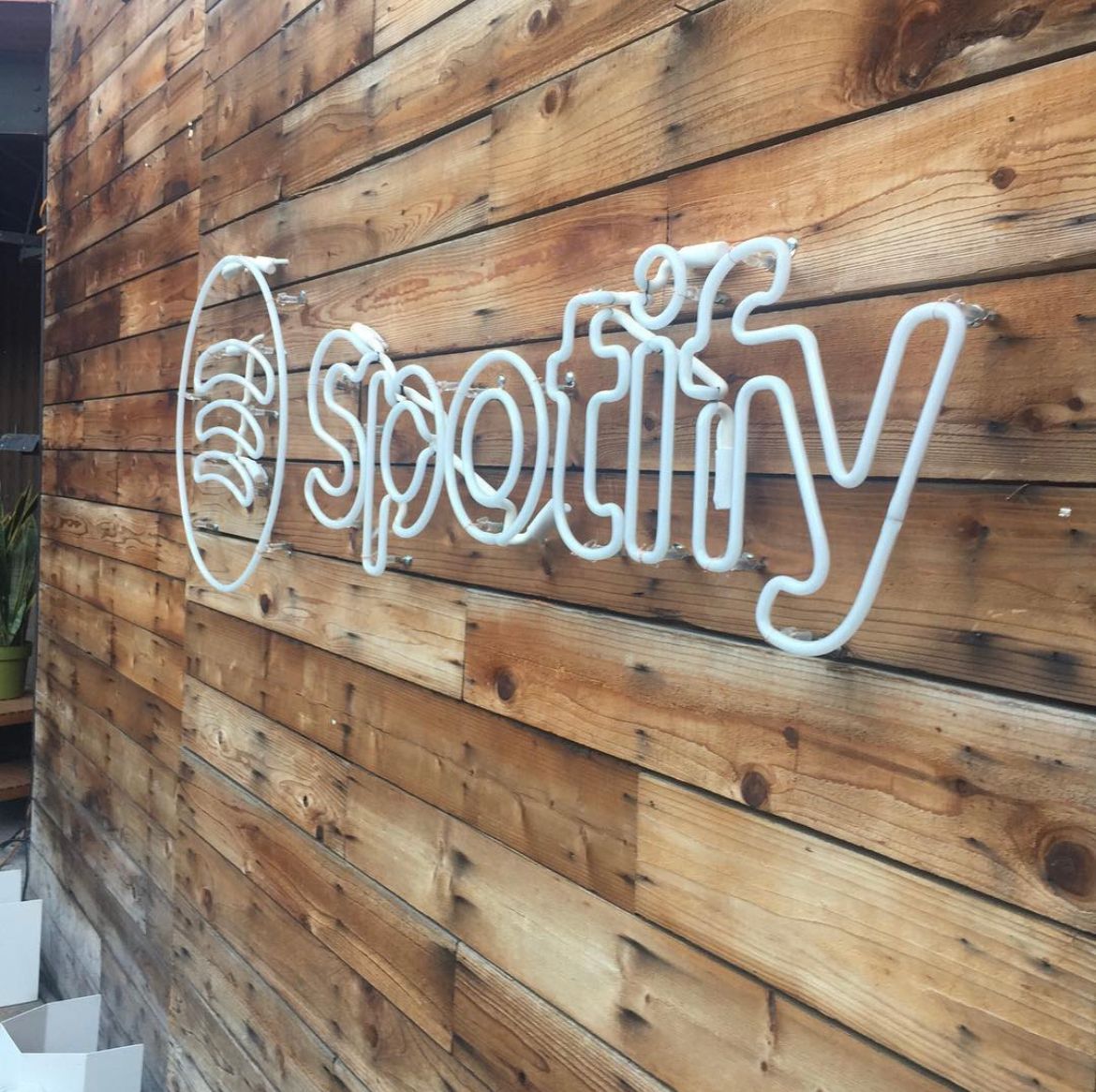 The word spotify is on a wooden wall