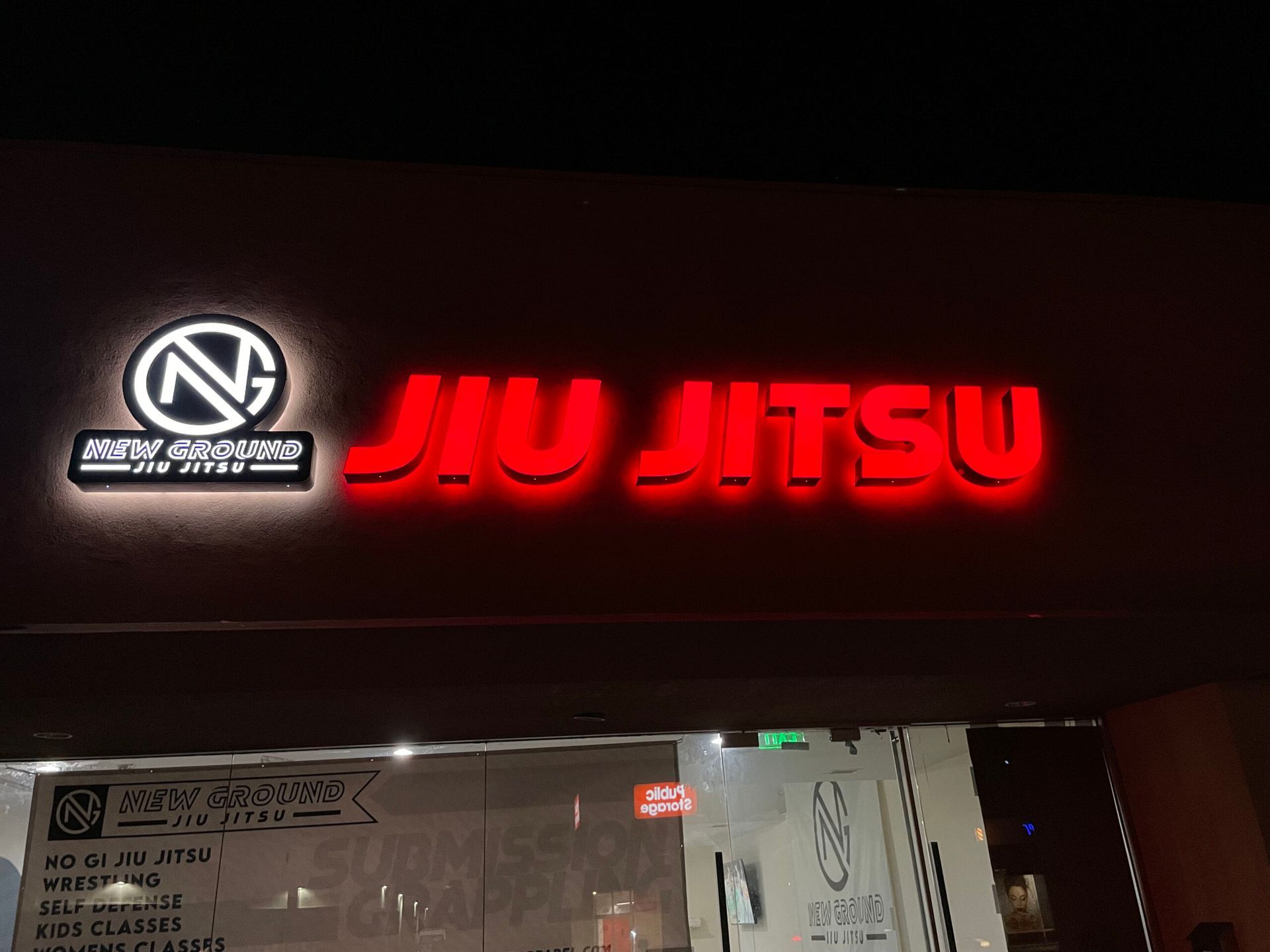 A jiu jitsu sign is lit up at night