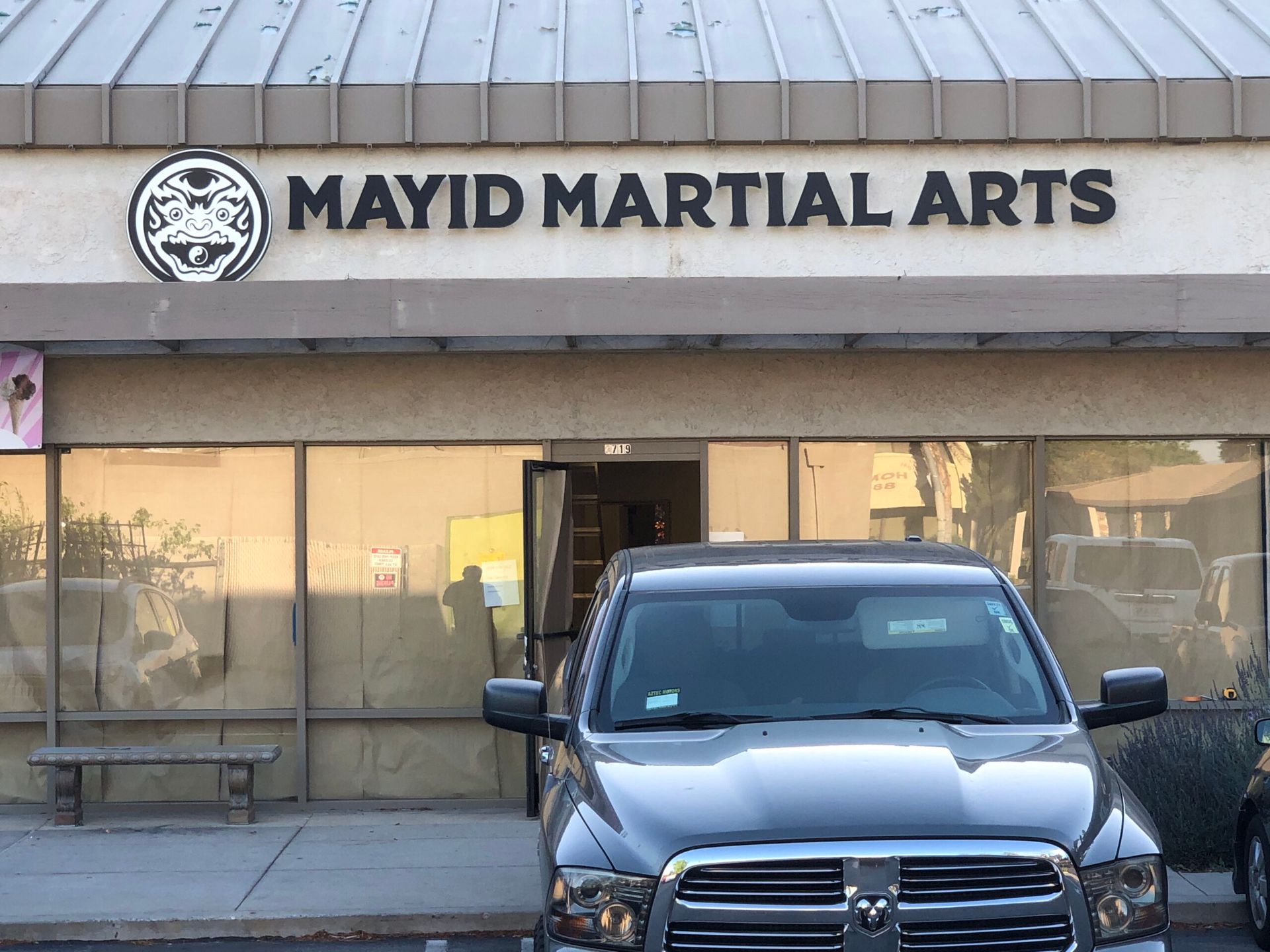A truck is parked in front of a mayid martial arts building