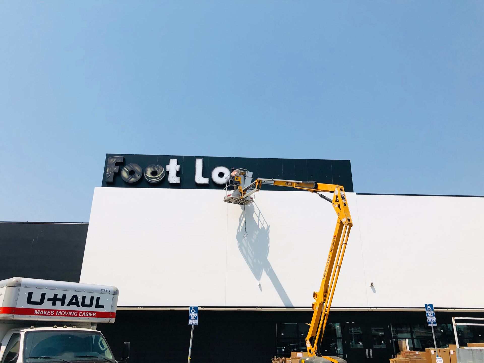 A u-haul truck is parked in front of a foot locker store.