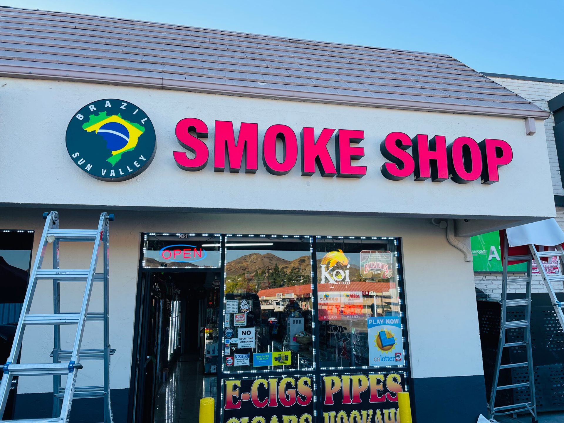 A smoke shop with a ladder in front of it