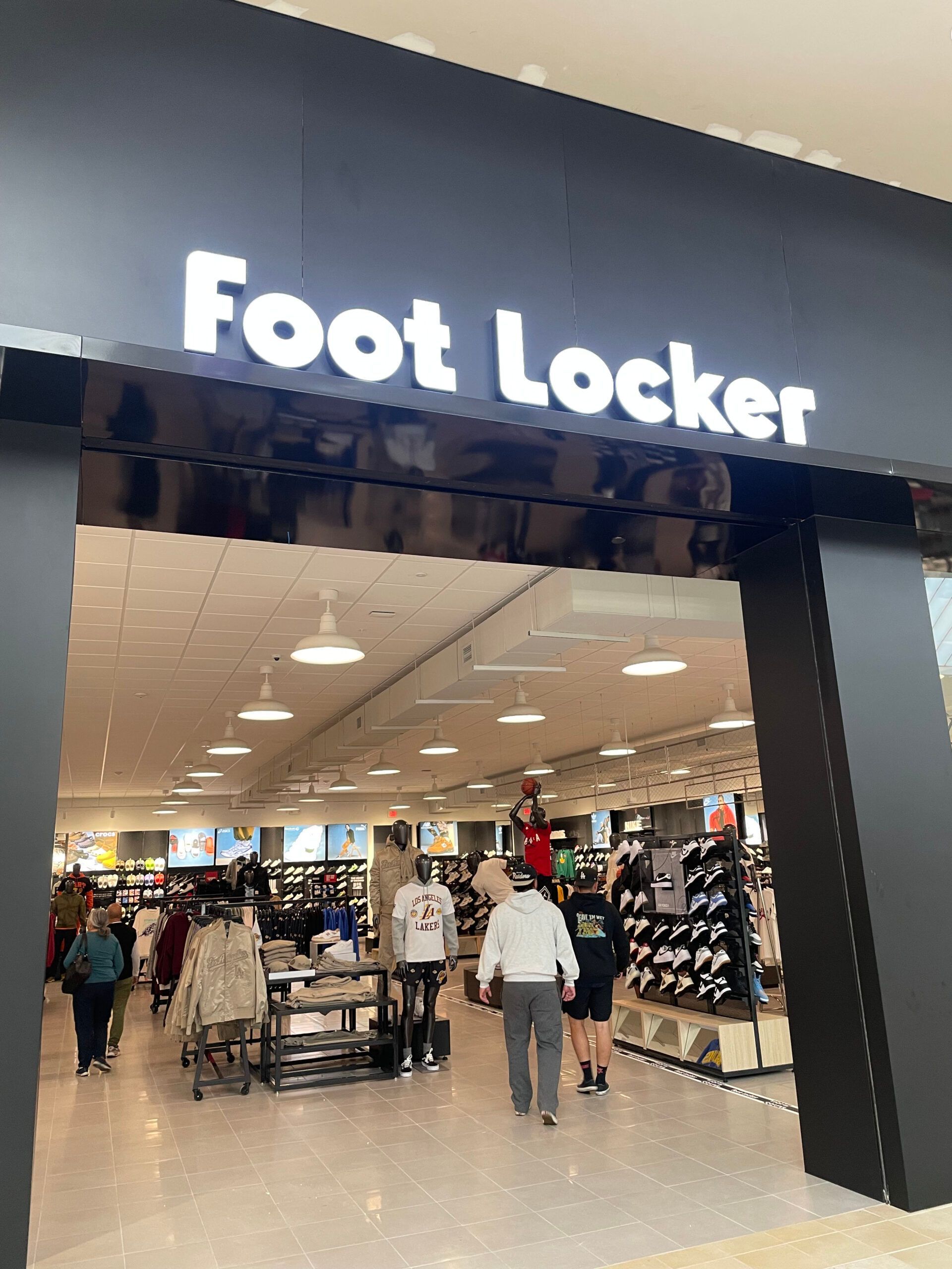 A foot locker store in a mall with people walking around