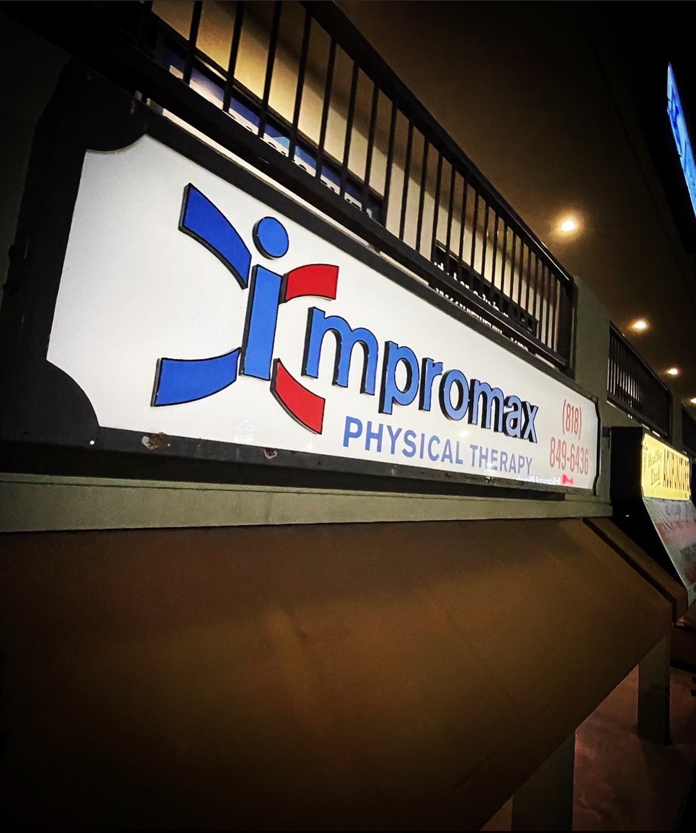 A sign for impromax physical therapy is above a staircase