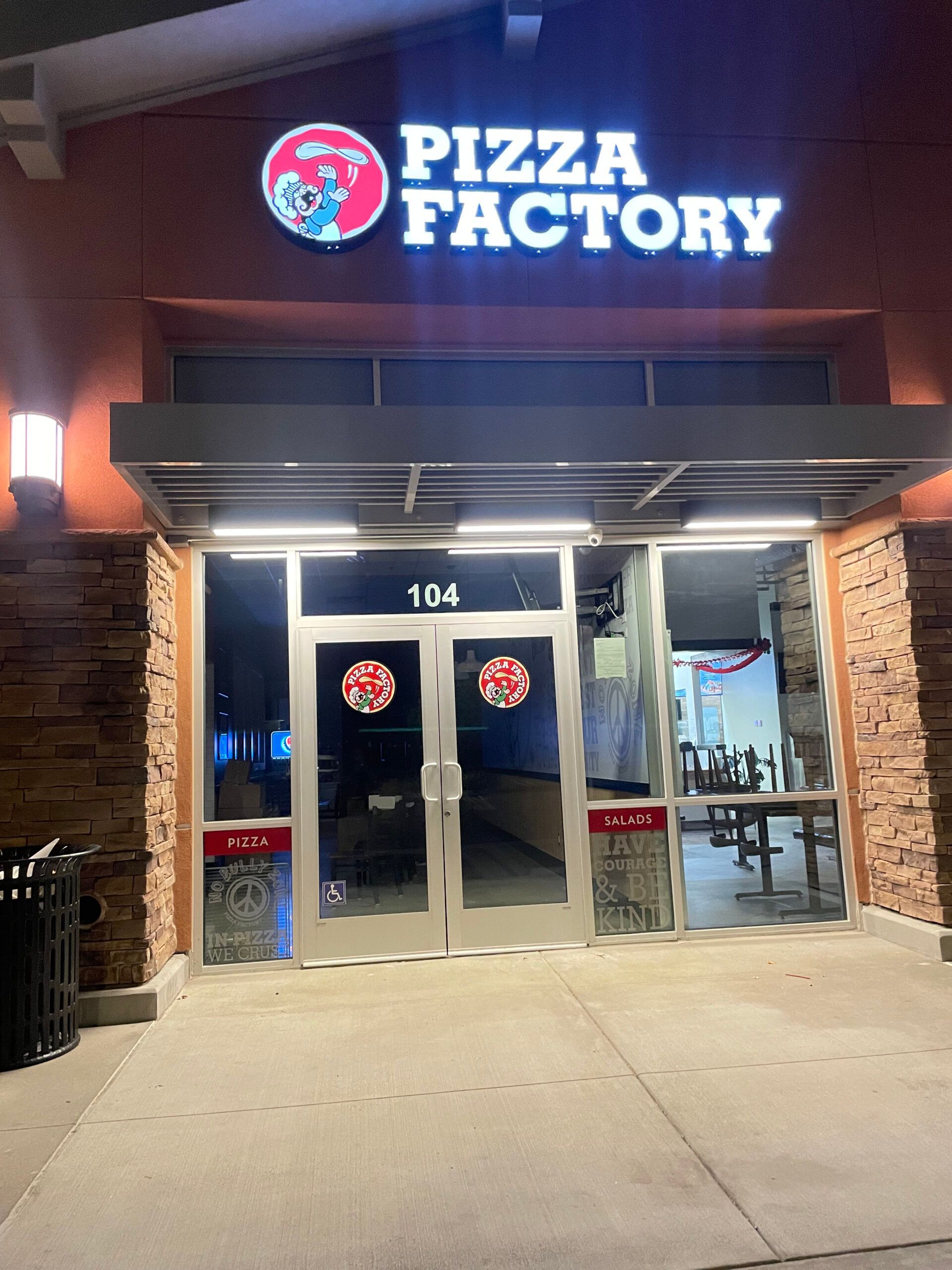 The front of a pizza factory restaurant at night
