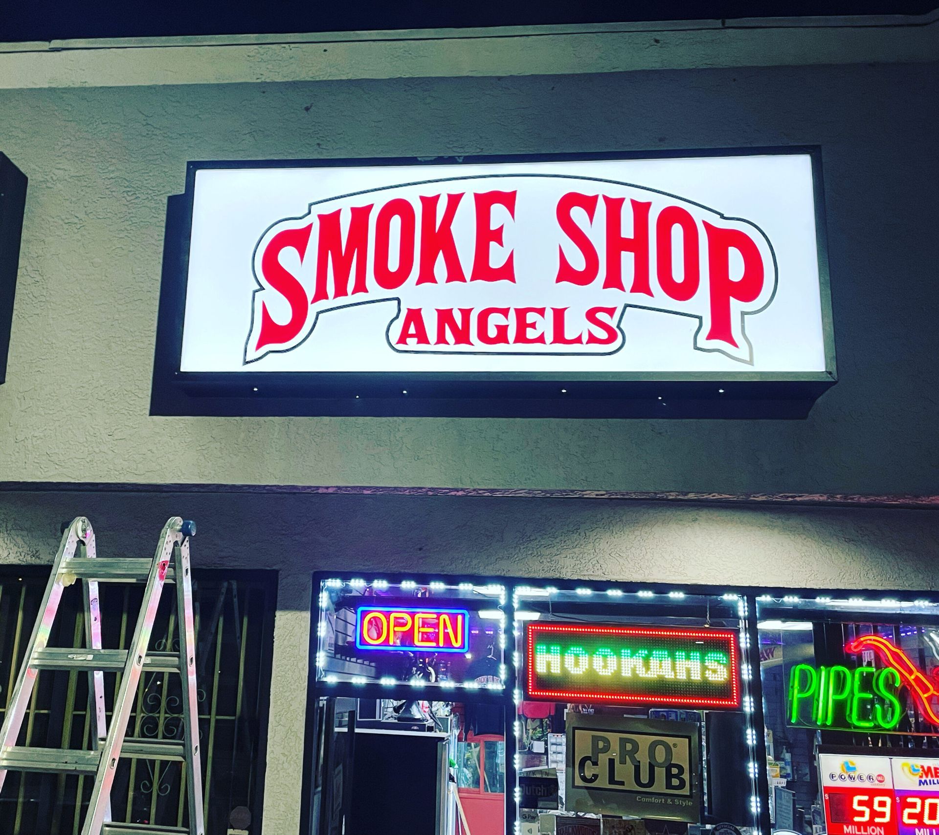 Smoke shop angels has a neon sign that says open