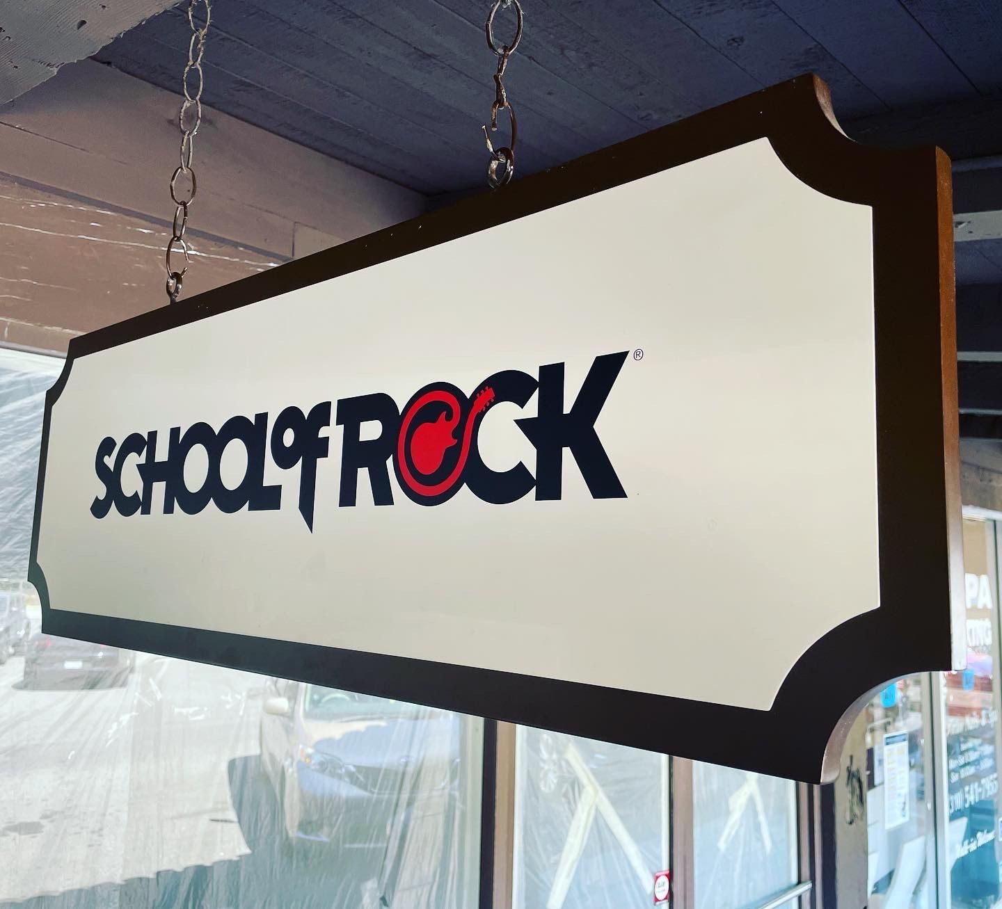 A sign for school of rock hangs from the ceiling