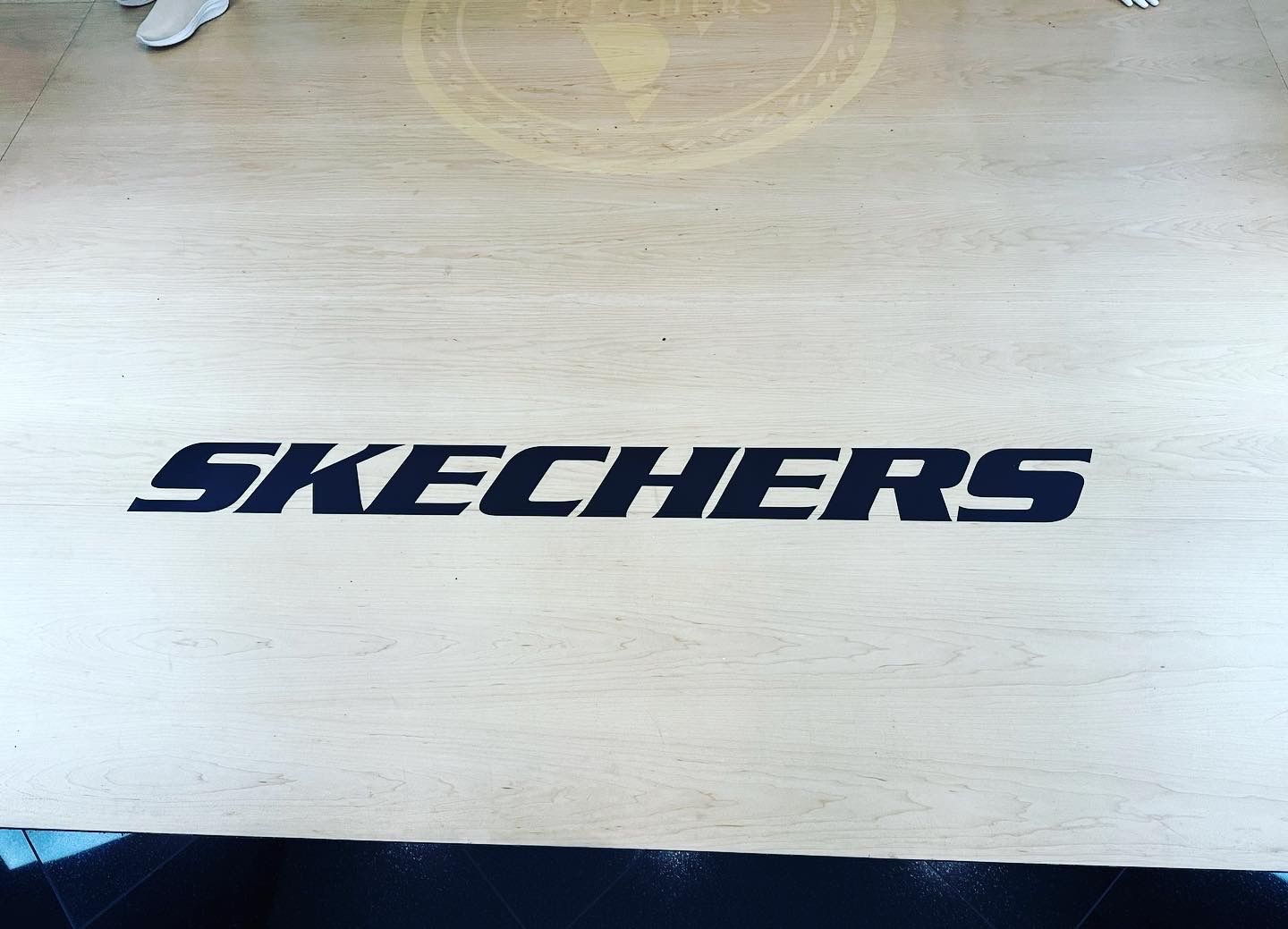 A wooden floor with the skechers logo on it