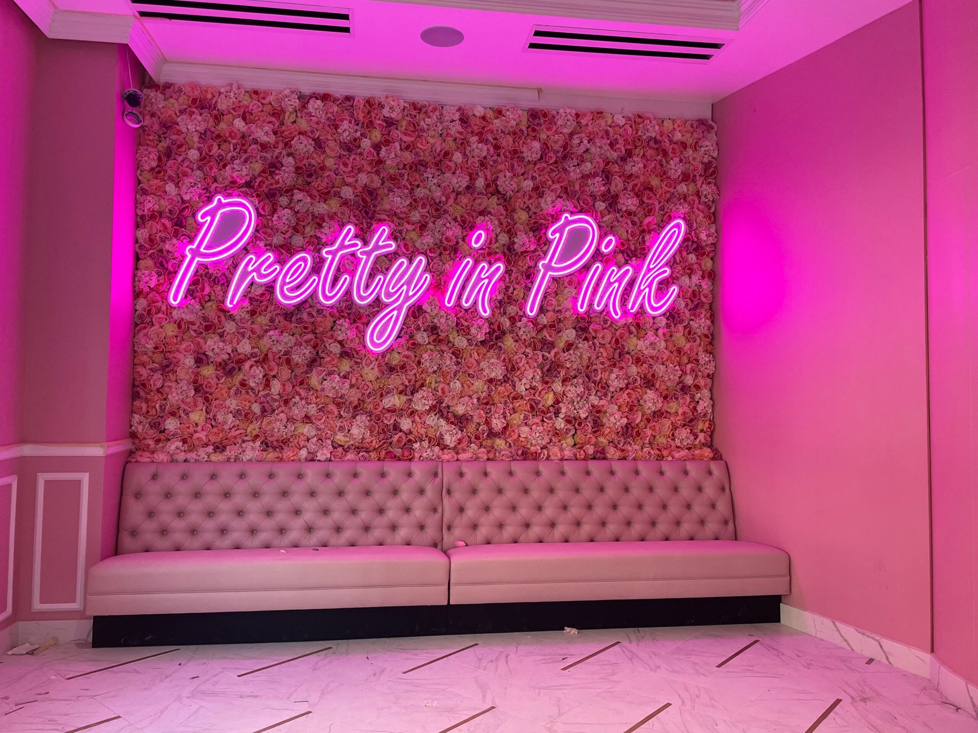 A room with pink walls and a neon sign that says