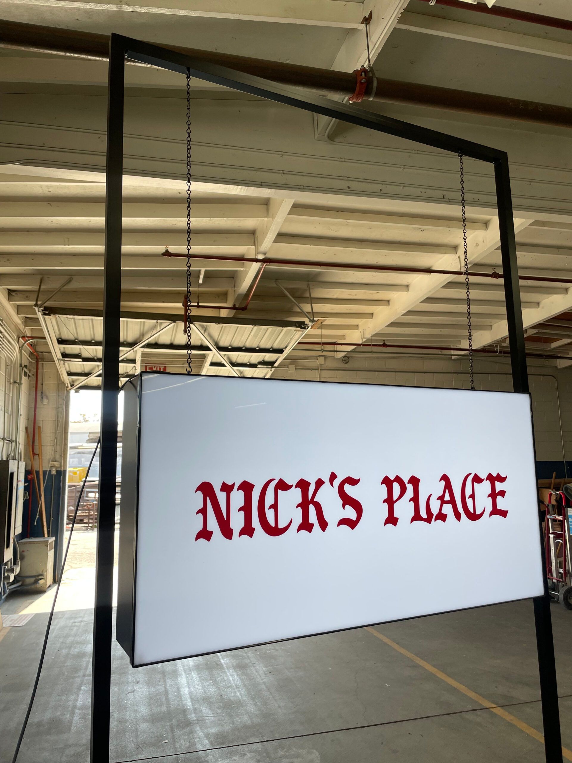 A sign for nick 's place hangs from the ceiling
