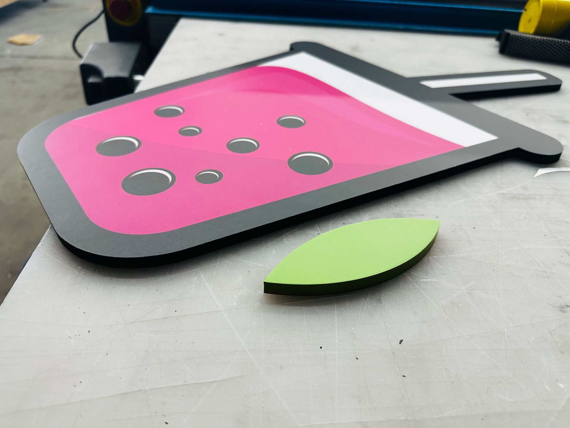 A pink and black watermelon drink with a green leaf on a table.