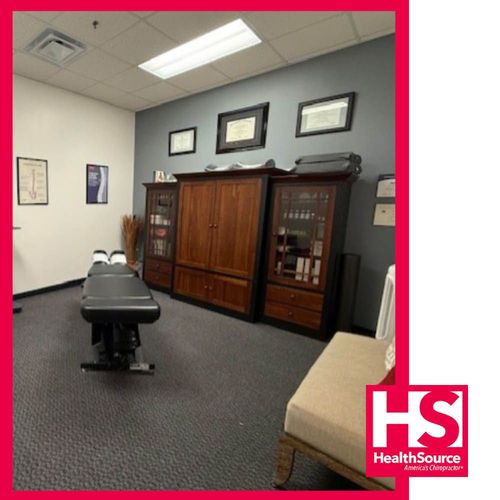 Exam room with wooden cabinets, framed certificates, and beige chair