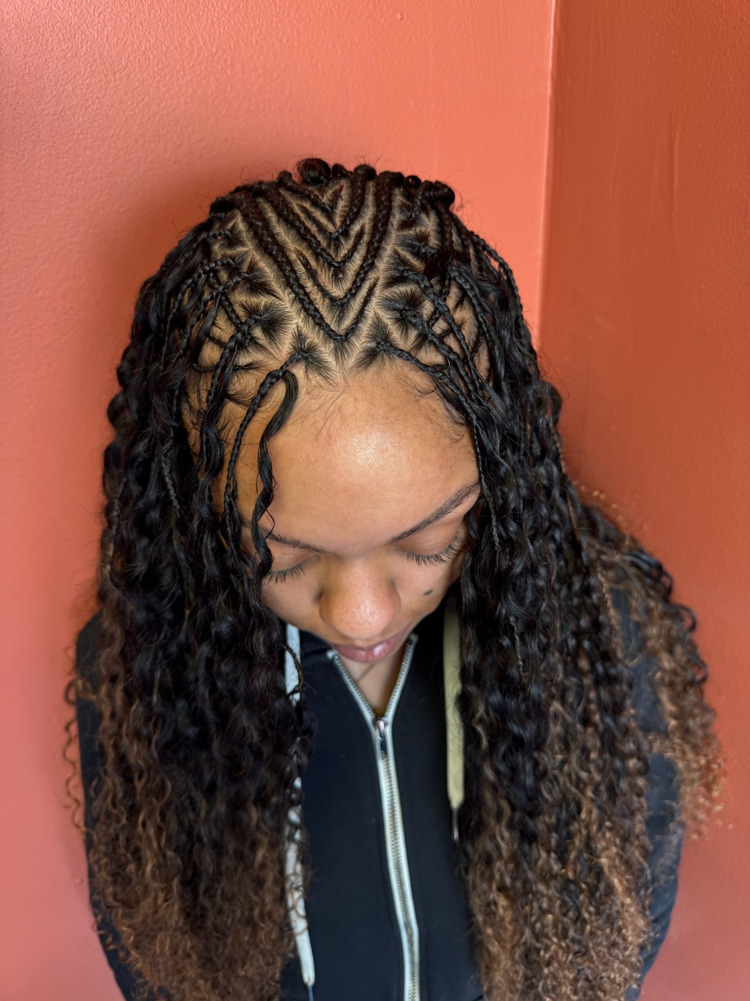 Woman with burgundy cornrow braids styled to the side, wearing a gray tank top.