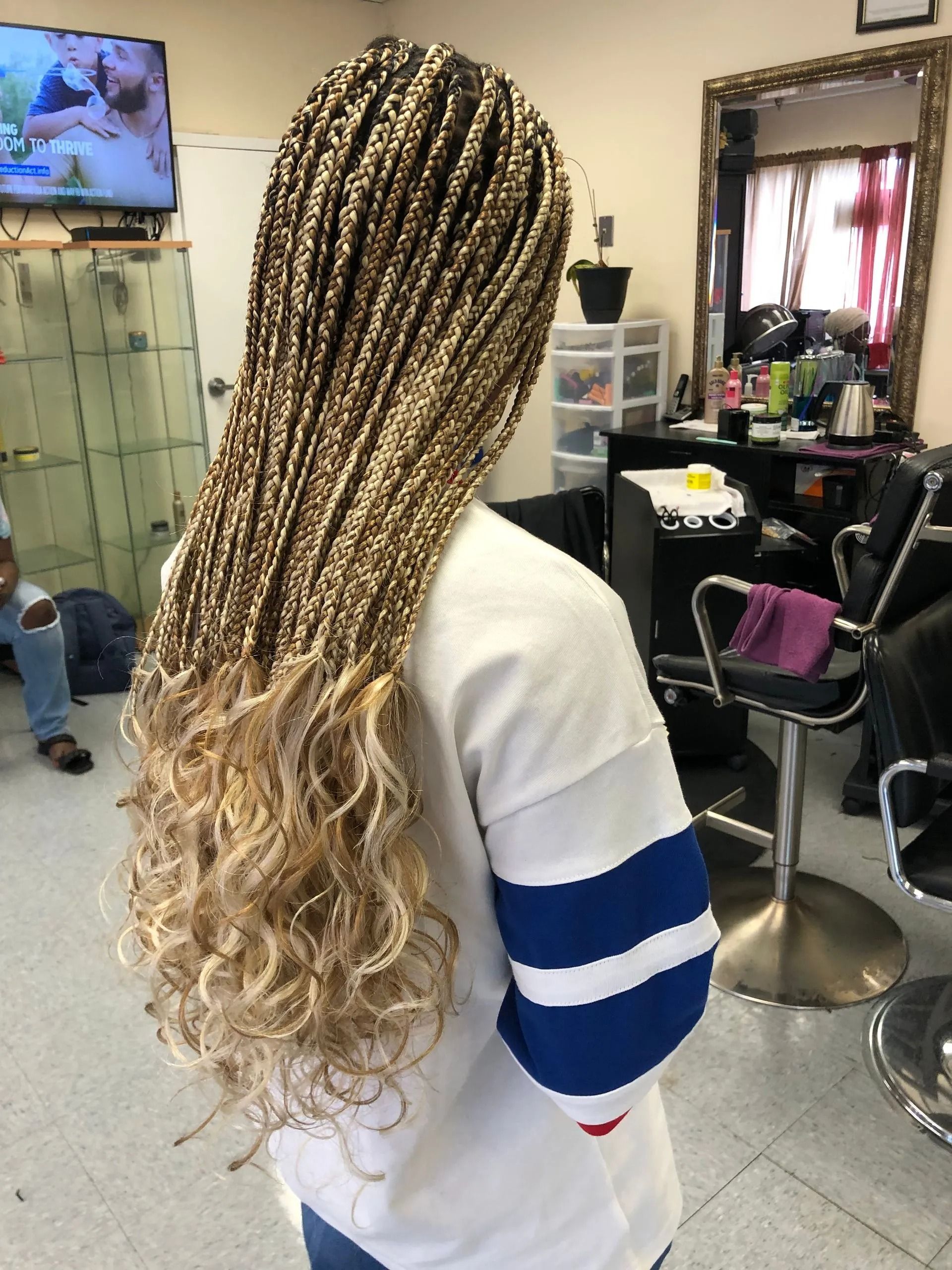 Woman with long blonde box braids, some with curly ends, in a salon.