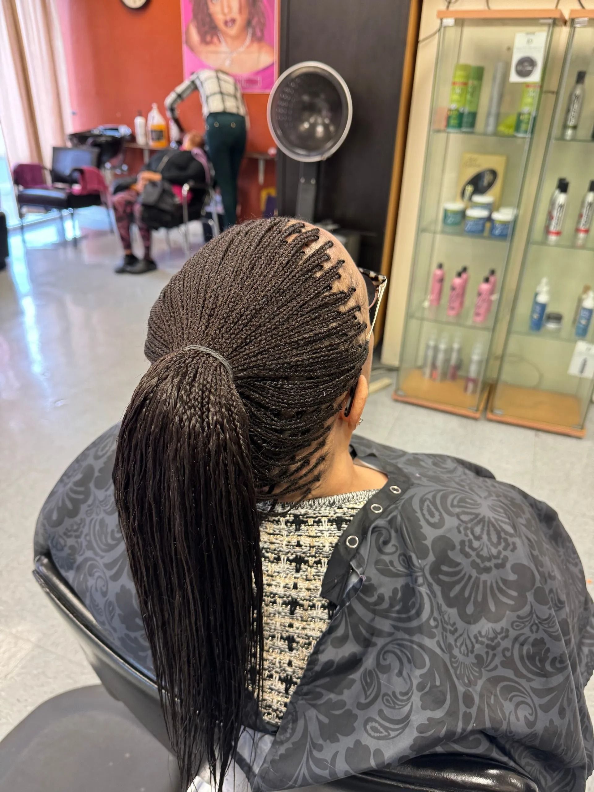 Woman in salon with micro braids in a ponytail, getting hair styled.