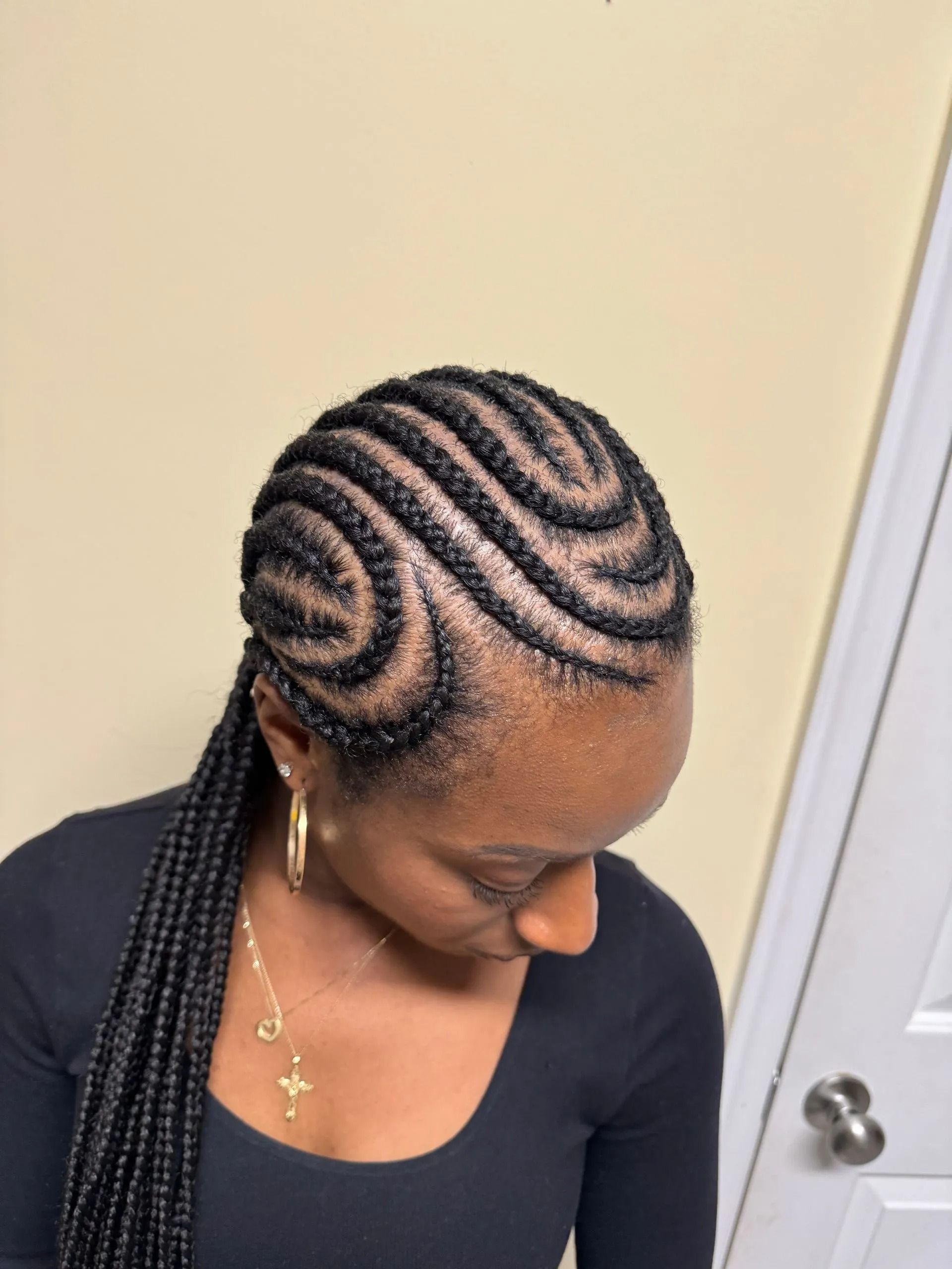 Woman with black cornrow braids in a wavy pattern, long braids in a ponytail.