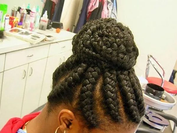 Woman with dark hair in a braided updo bun, in a salon setting.