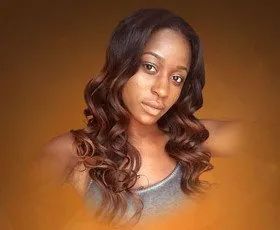 Woman with long, wavy brown hair, wearing a gray tank top, with a neutral expression, against an orange background.