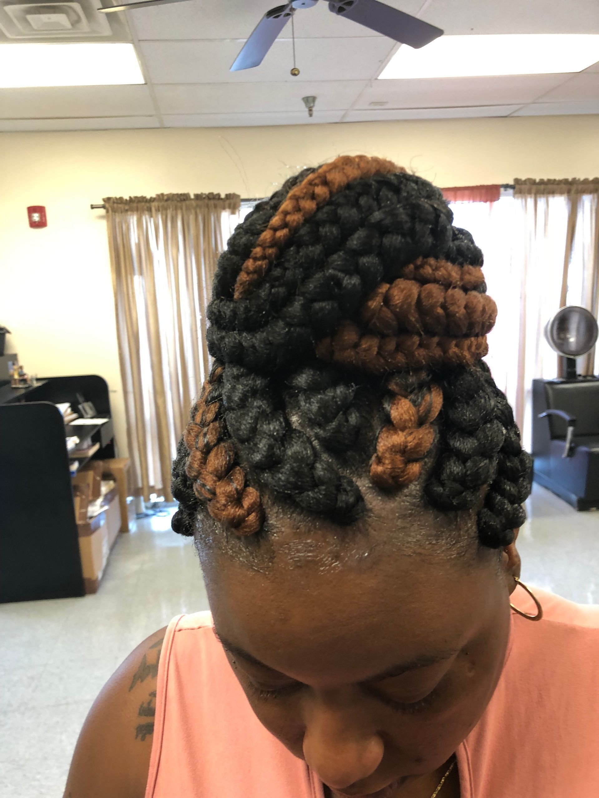 Woman with black and brown braided updo, indoors.