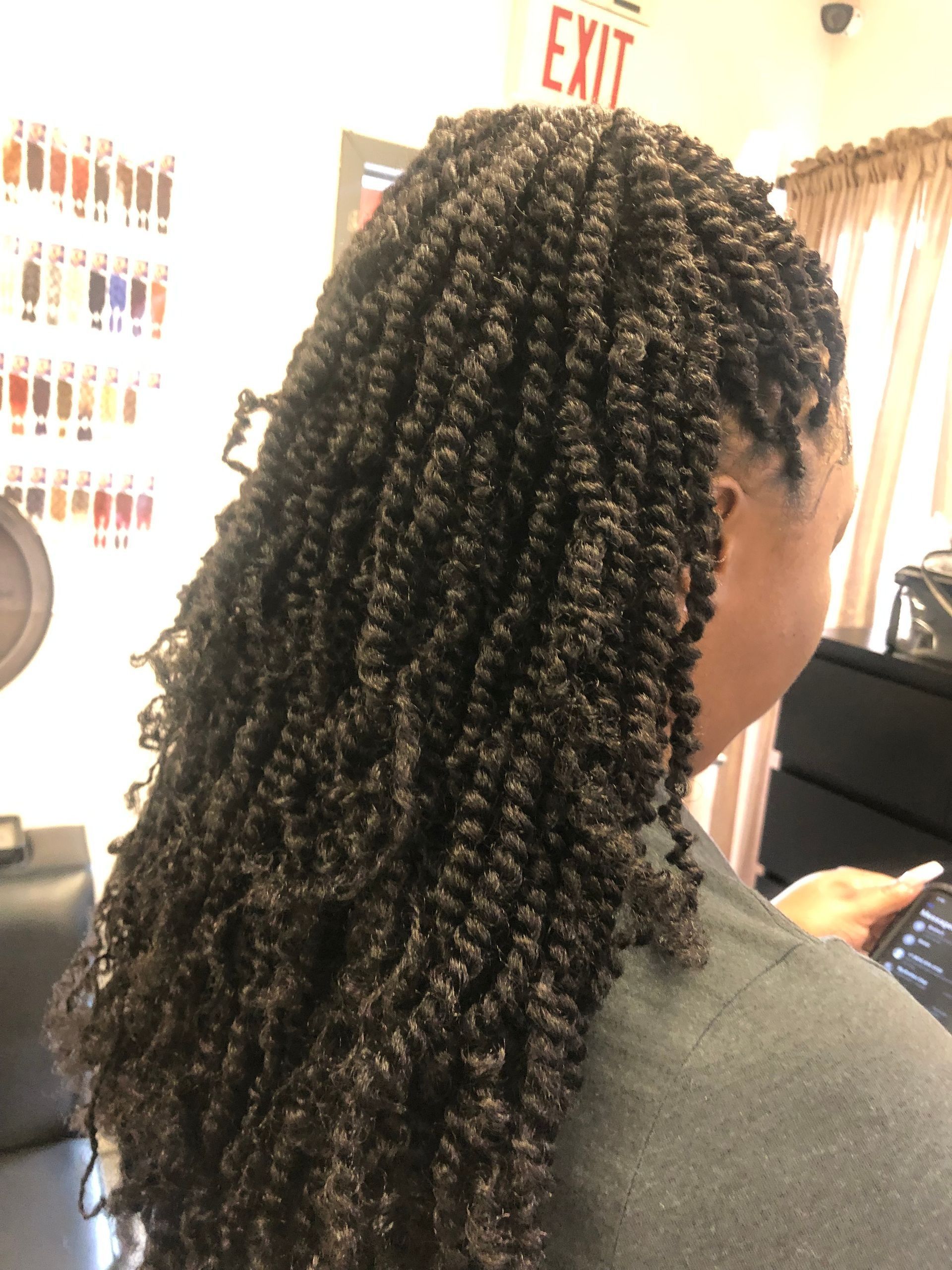 Woman with long, dark brown twists hairstyle, seated in a salon.