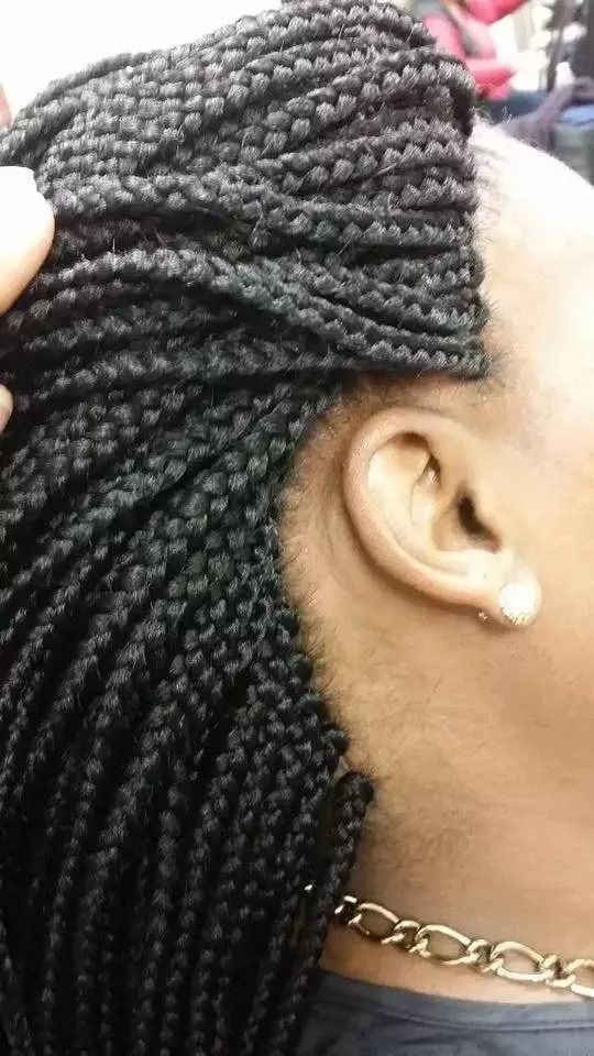 Close-up of a person's braided black hair, including ear and gold necklace.