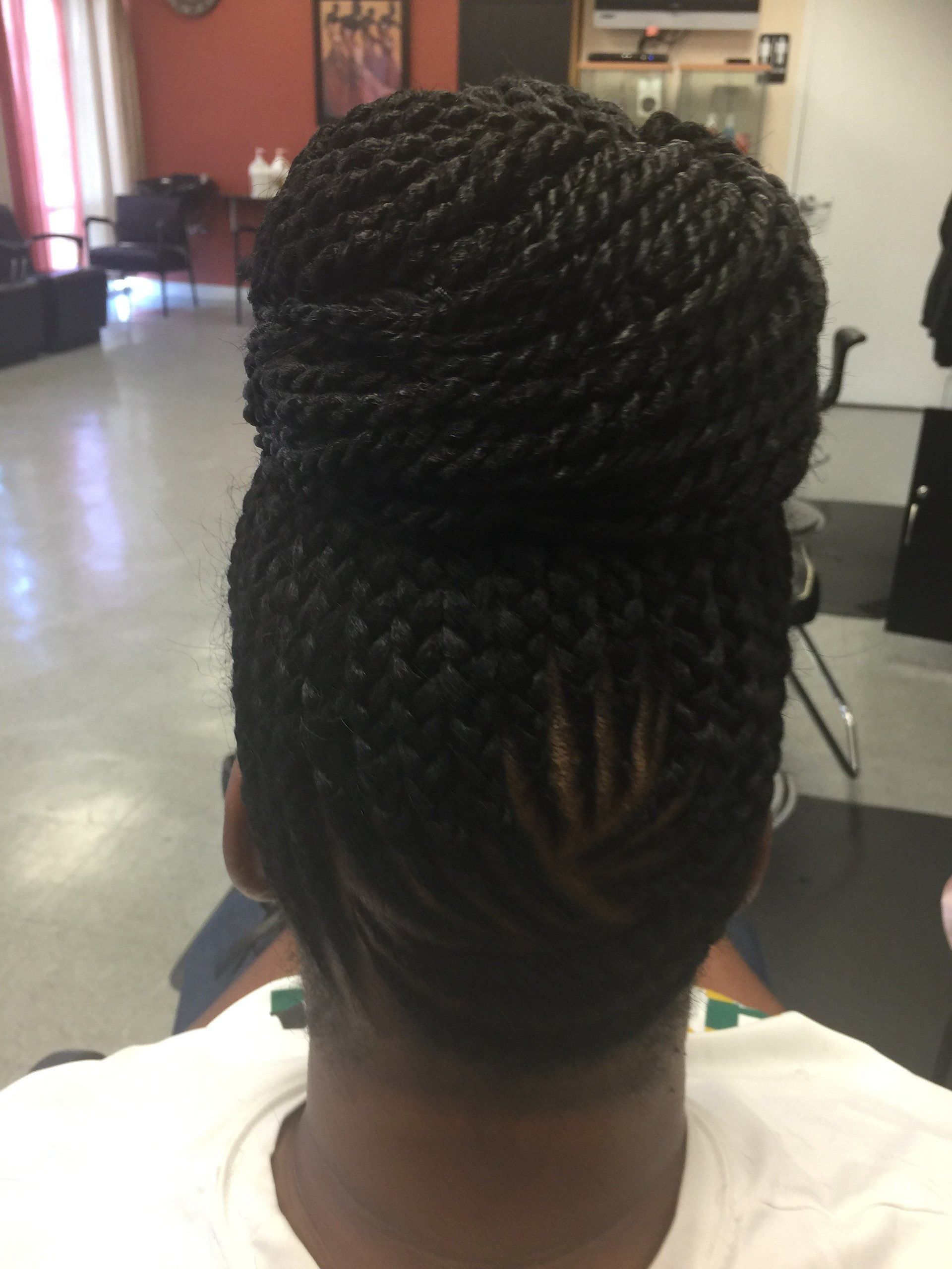 Woman with black twists in a high bun hairstyle, indoors.