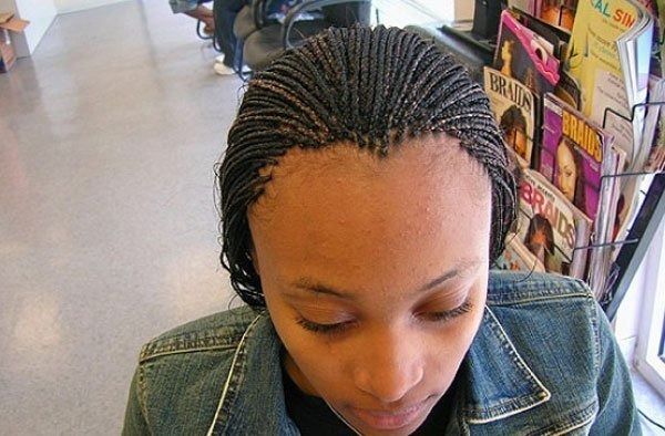 Woman with braided hair and denim jacket, looking down.