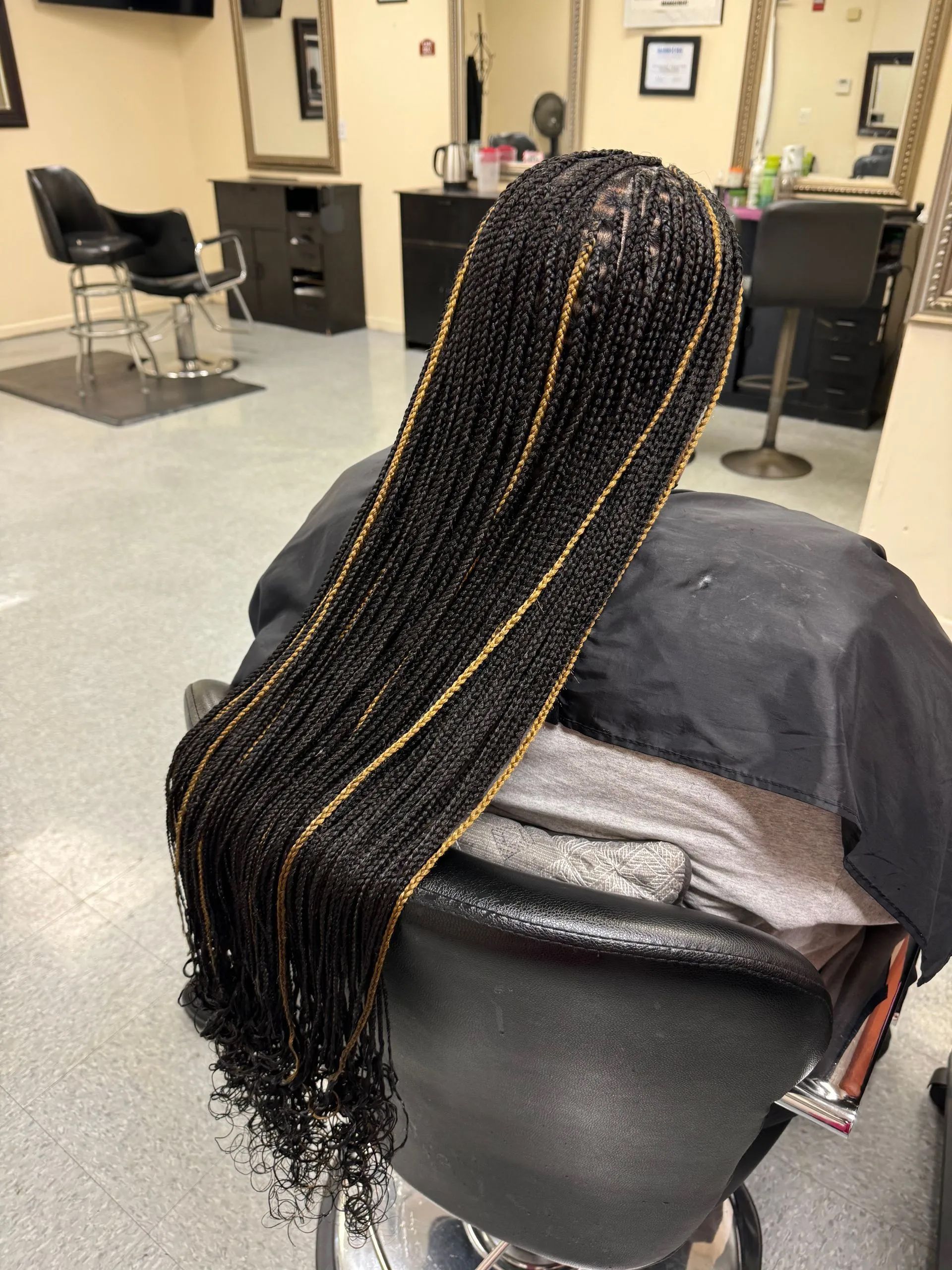 Braided black hair with gold highlights, salon chair.