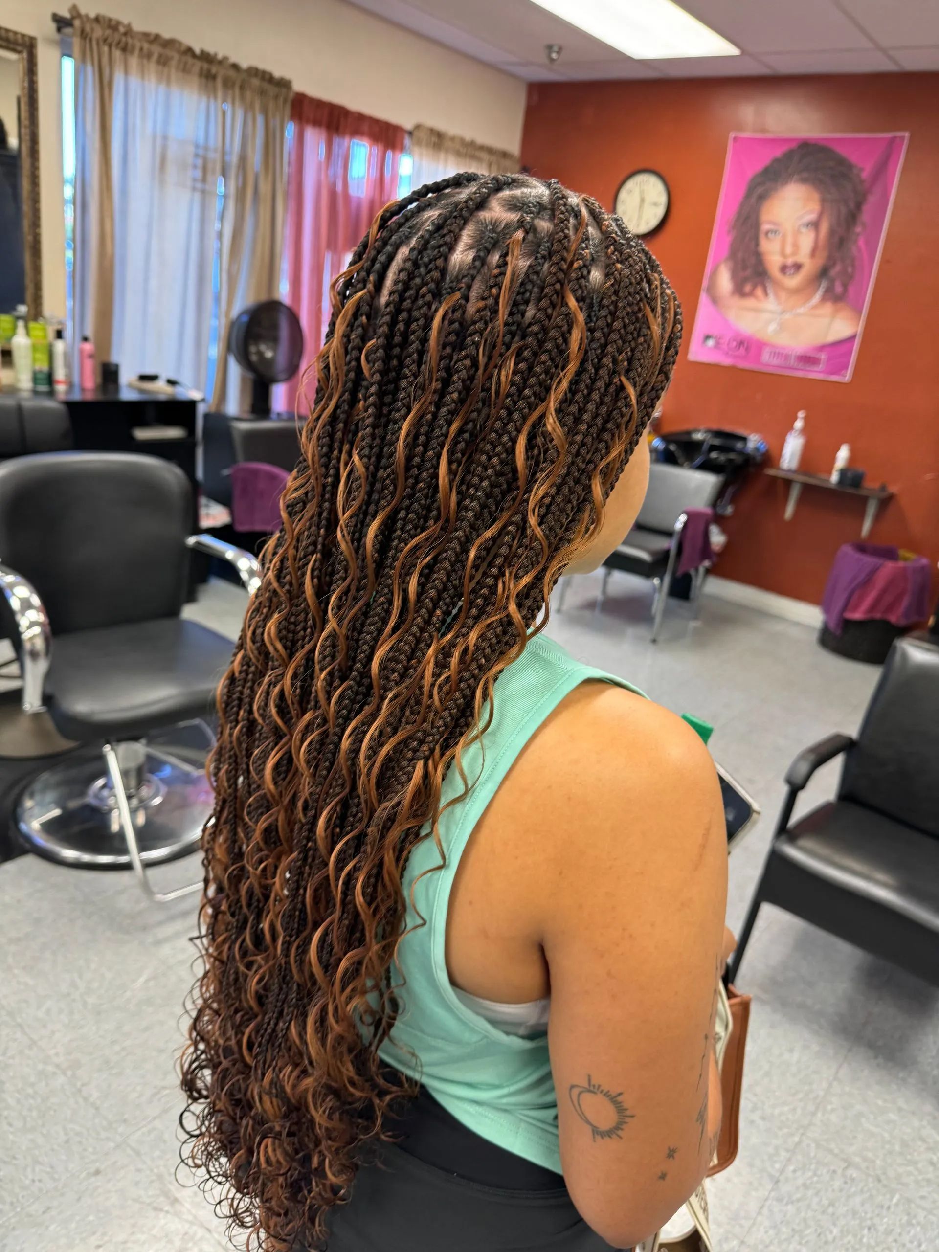 Woman with long, curly, two-toned braids in a hair salon.