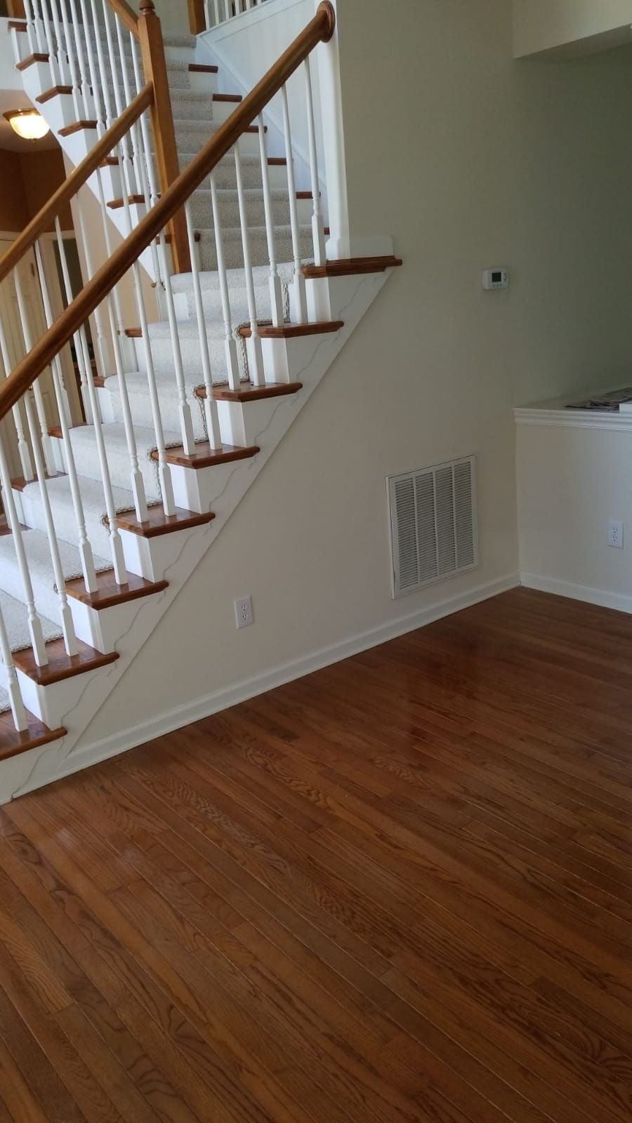 A staircase with wooden steps and white railings in an empty room