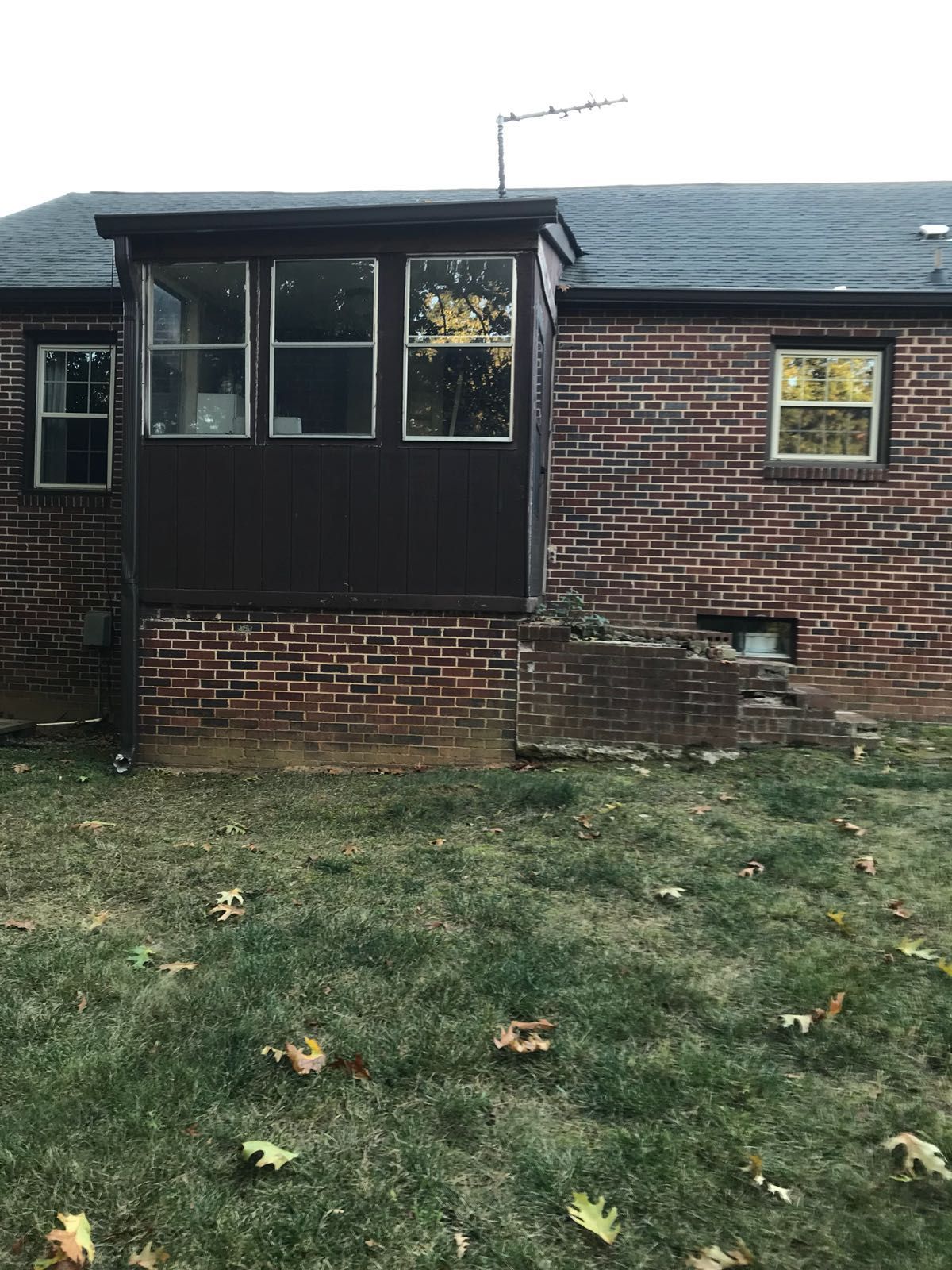 The back of a brick house with a screened in porch.