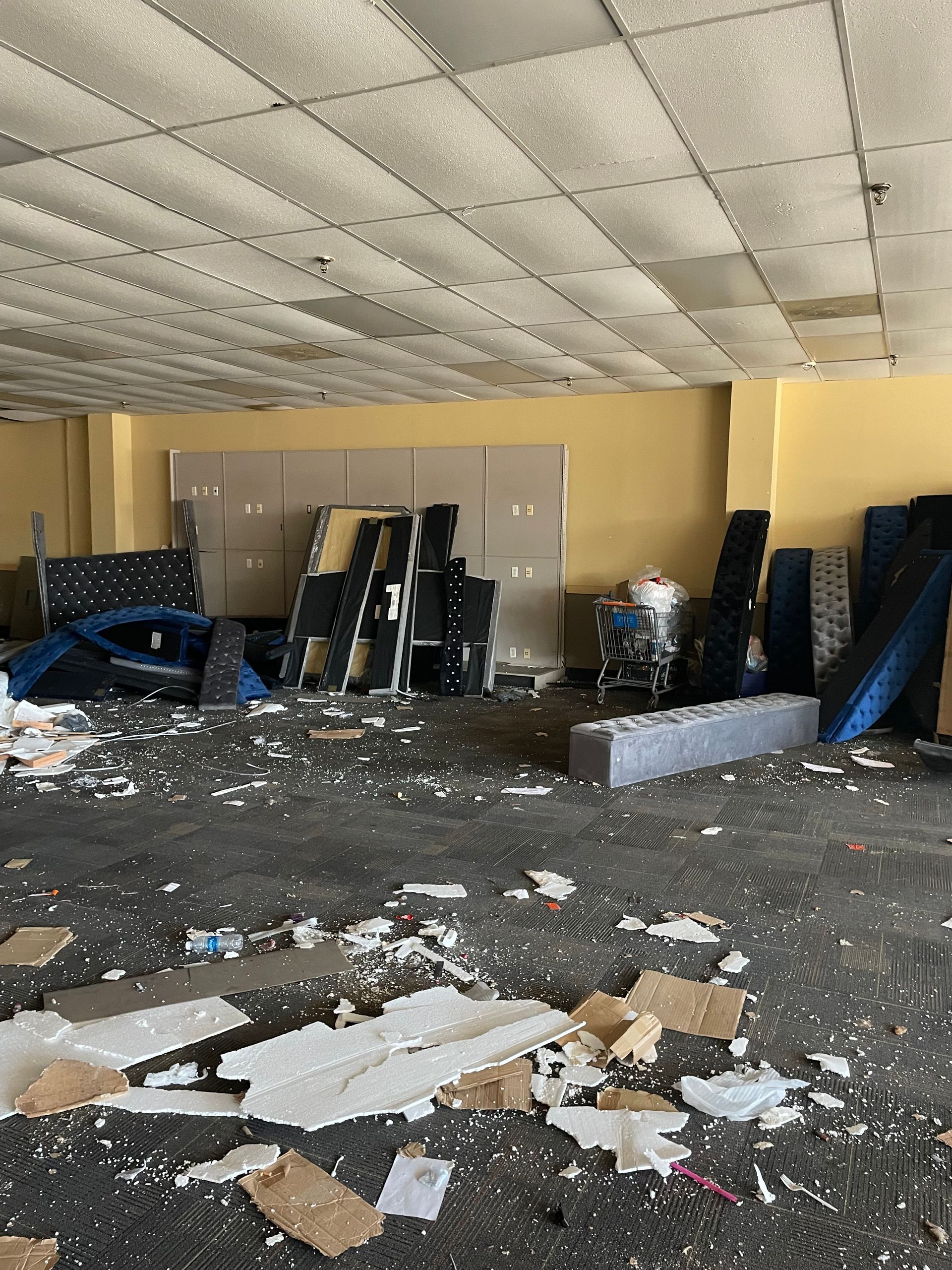 An empty room with a lot of trash on the floor.