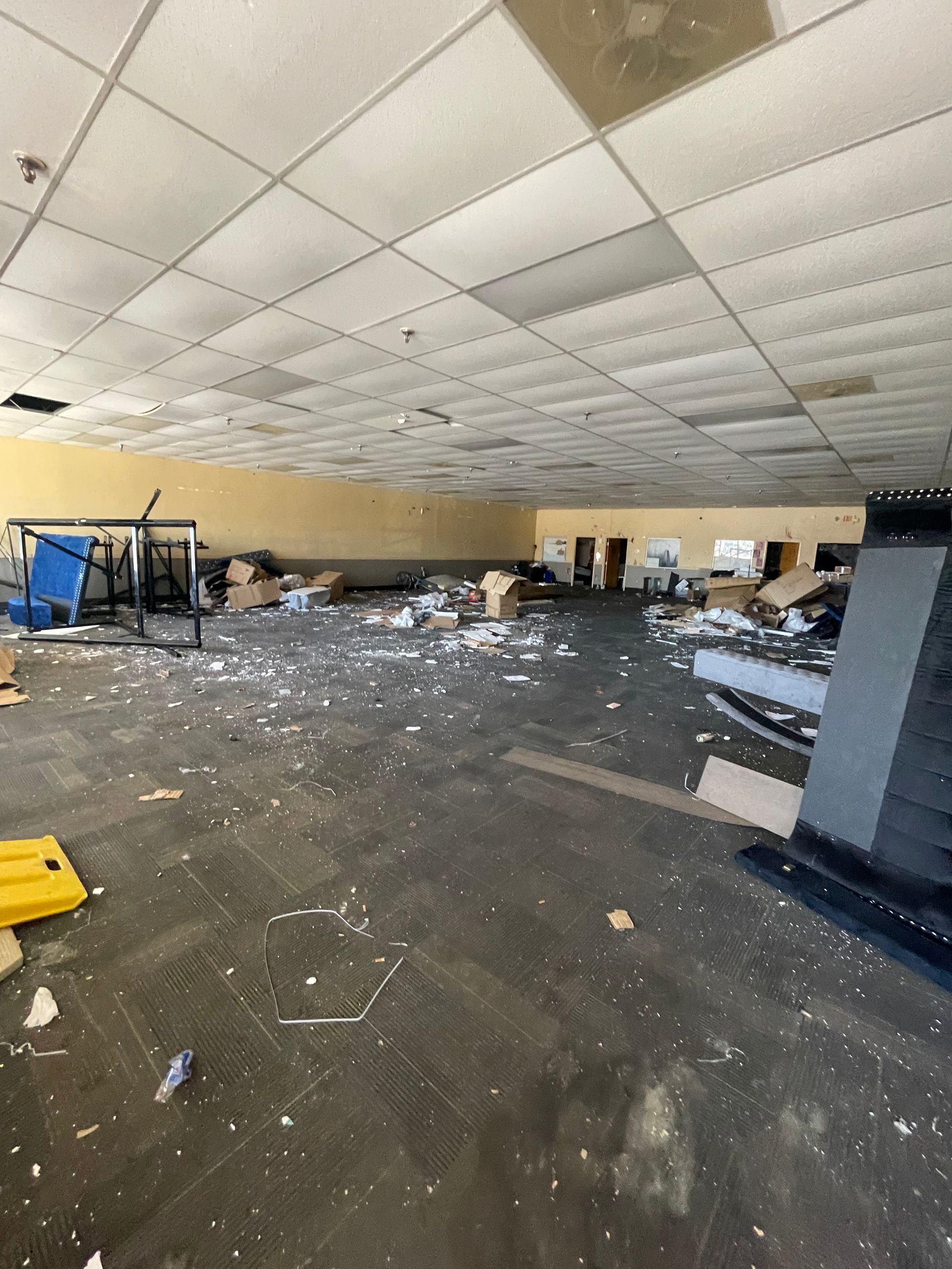 An empty room with a lot of trash on the floor and ceiling.
