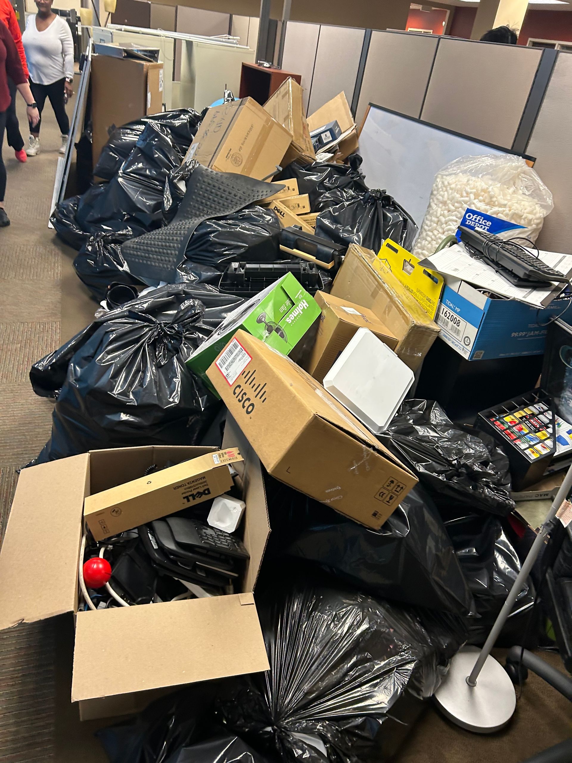 A pile of garbage bags and boxes in an office