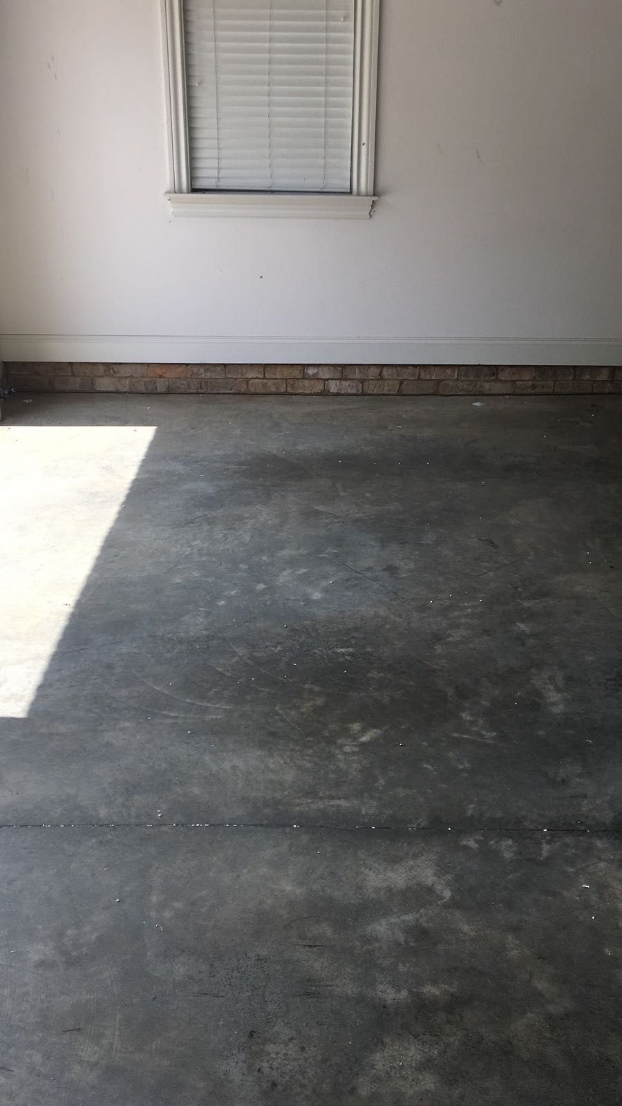 An empty garage with a window and a concrete floor.