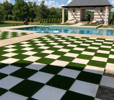 A checkered patio with alternating grass and stone pavers leads to a backyard swimming pool and open-air gazebo.