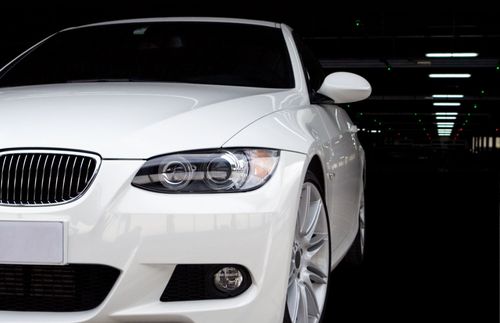 White BMW sedan parked in a dark garage, front view