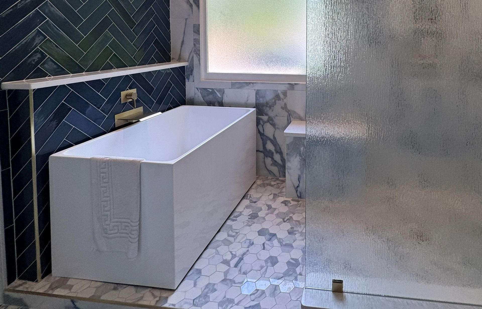 Modern bathroom with white tub, glass shower, and blue tiled wall.