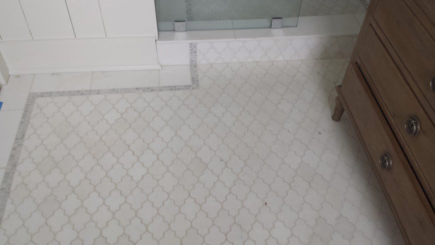 Bathroom floor with patterned tiles and wooden dresser.
