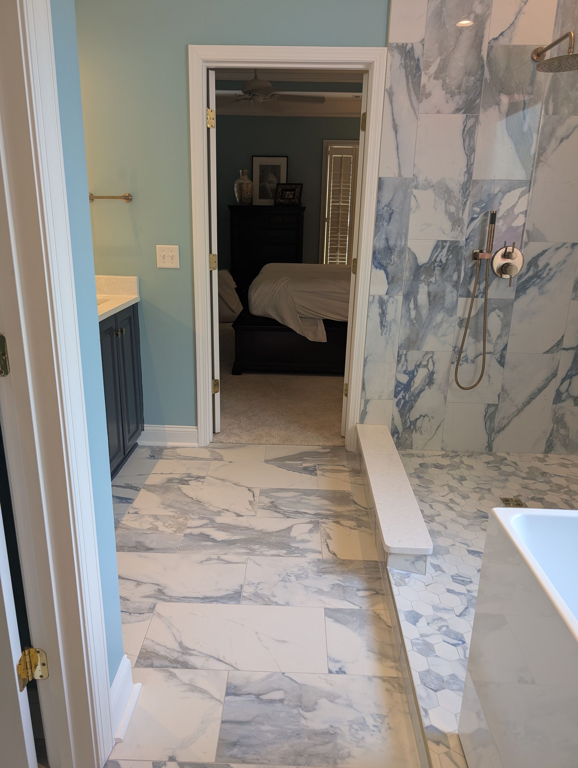 Bathroom entrance with blue marble tile, doorway to bedroom, and light blue walls.
