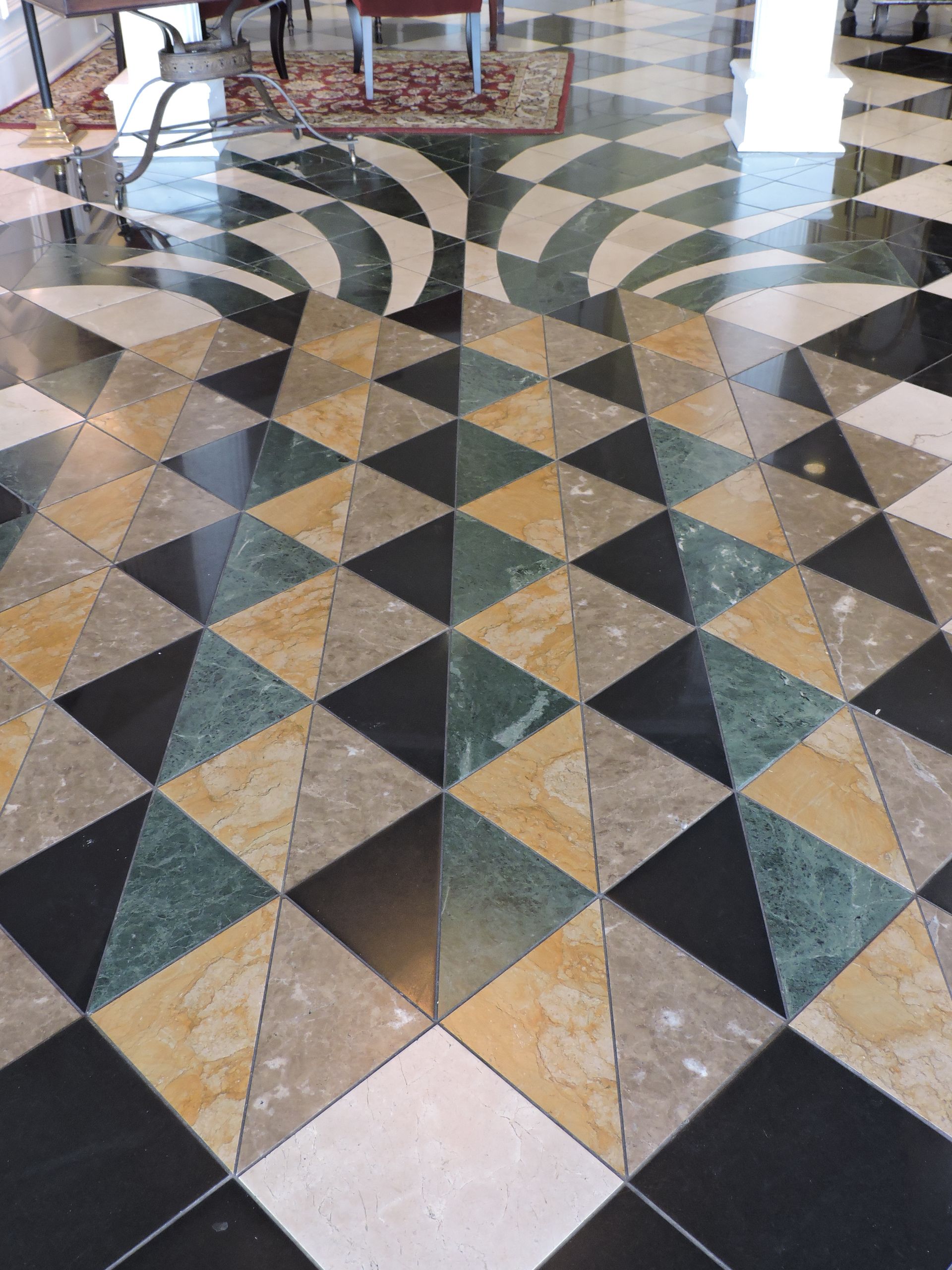 Geometric marble floor with triangles and curved patterns in black, gold, green, and gray.