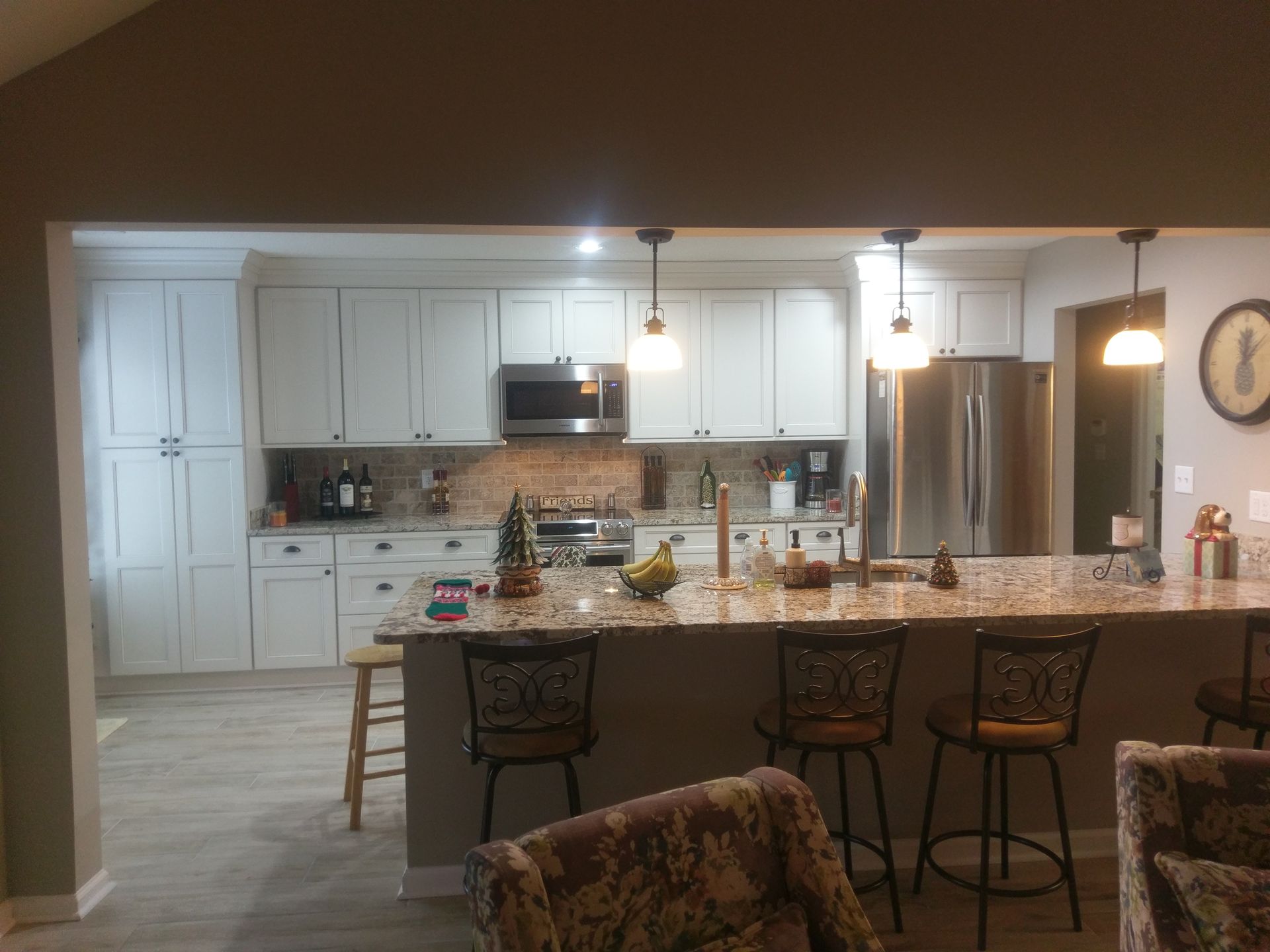Kitchen with white cabinets, island with stools, and stainless steel appliances.