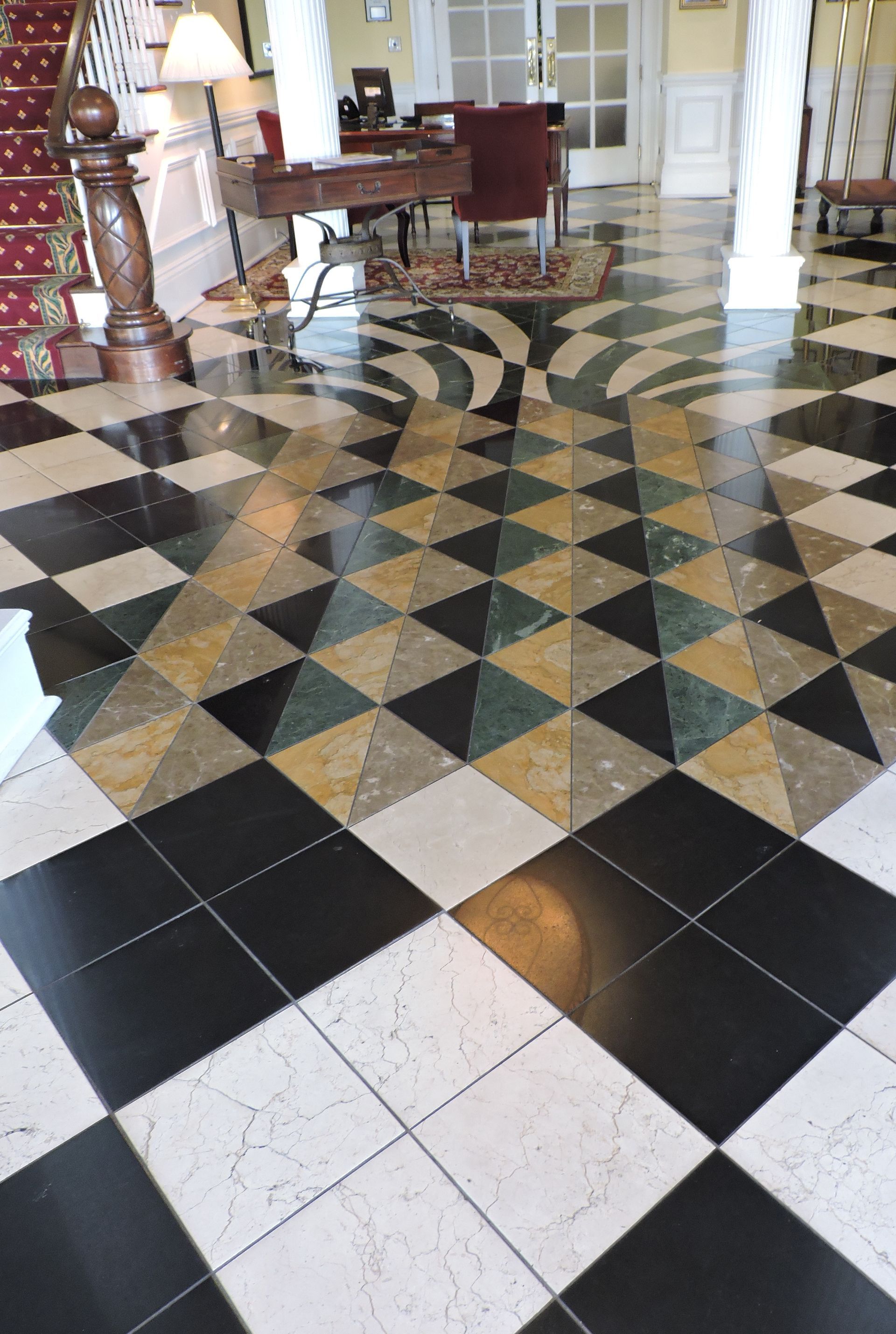 Checkered marble floor with a geometric pattern, leading to a lobby area with furniture.