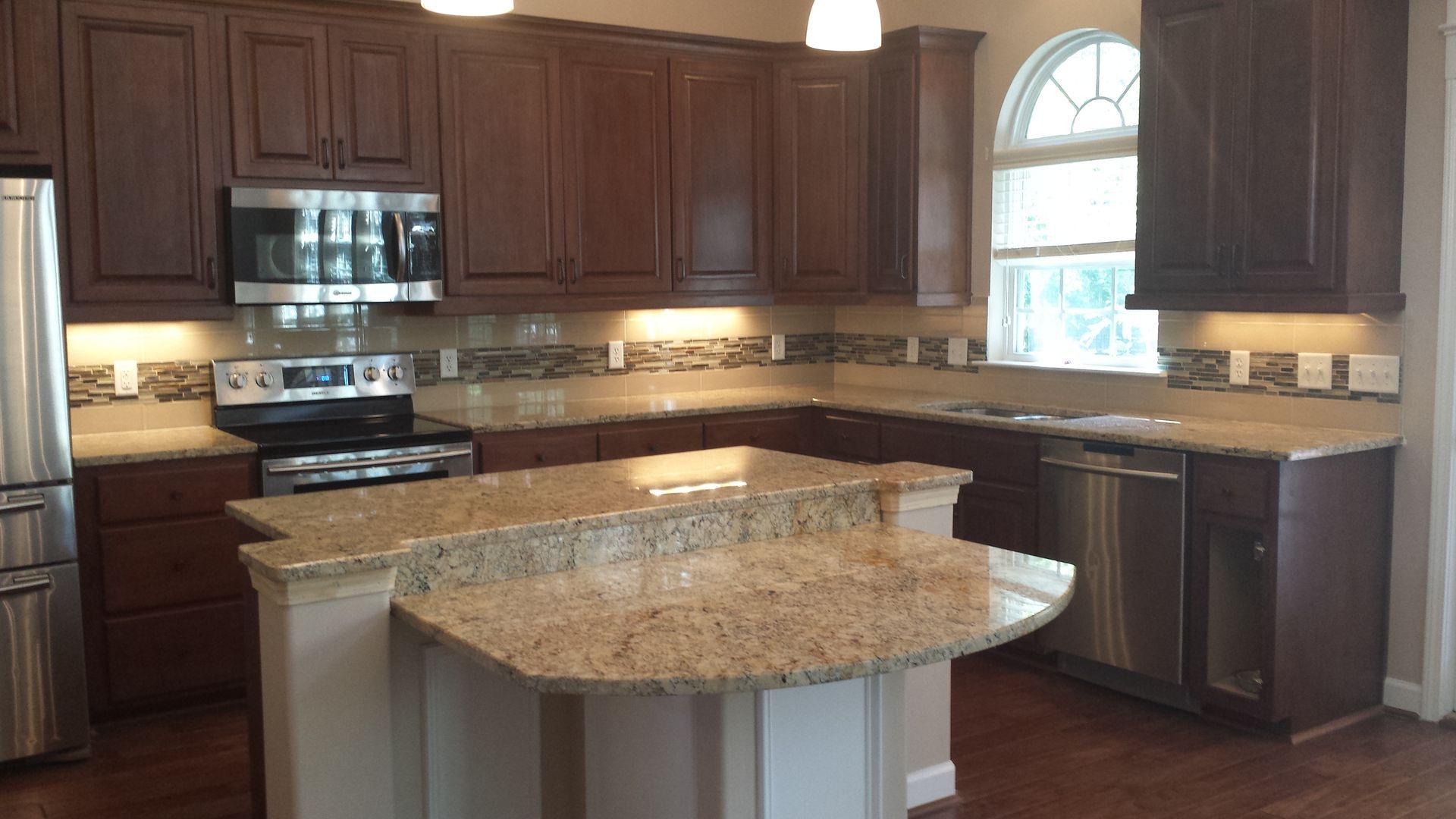 Kitchen with dark cabinets, light countertops, stainless steel appliances, and a central island.