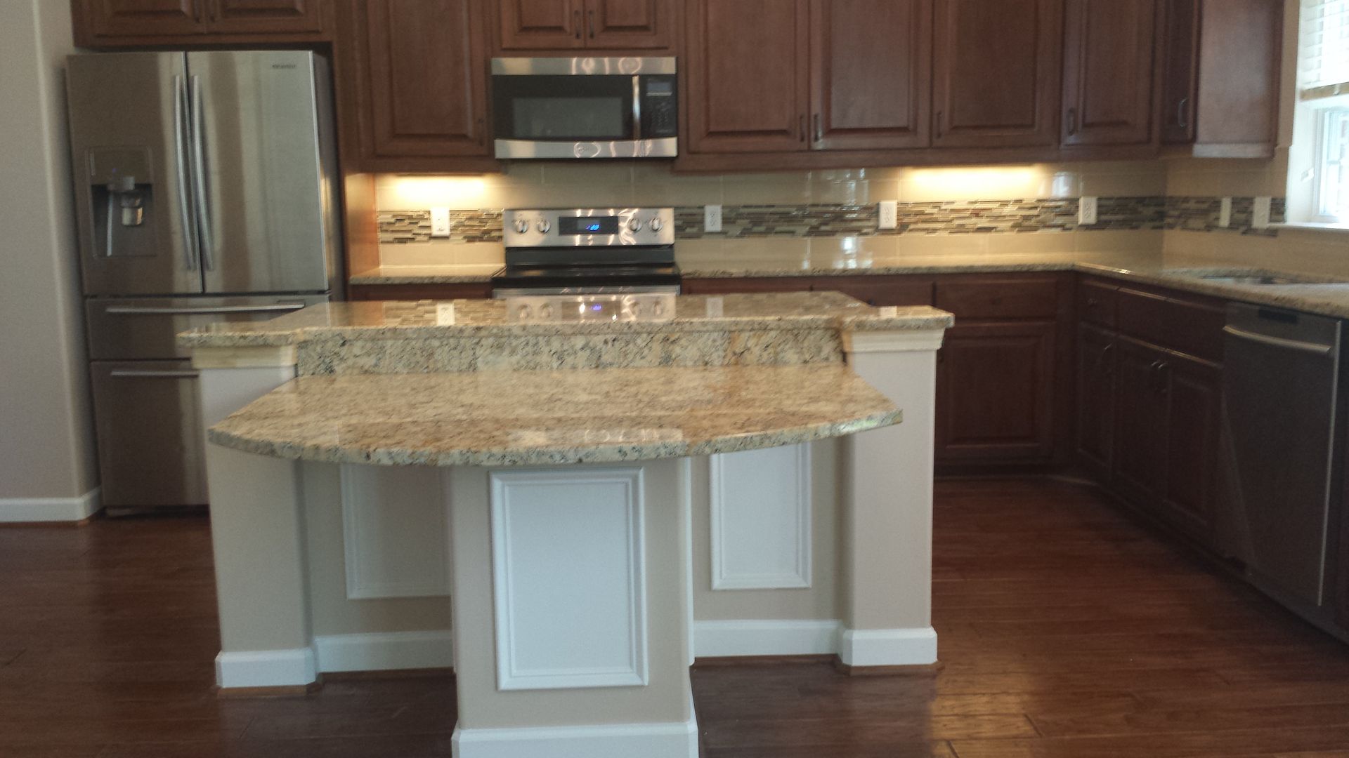Kitchen with dark brown cabinets, granite countertops, and stainless steel appliances.